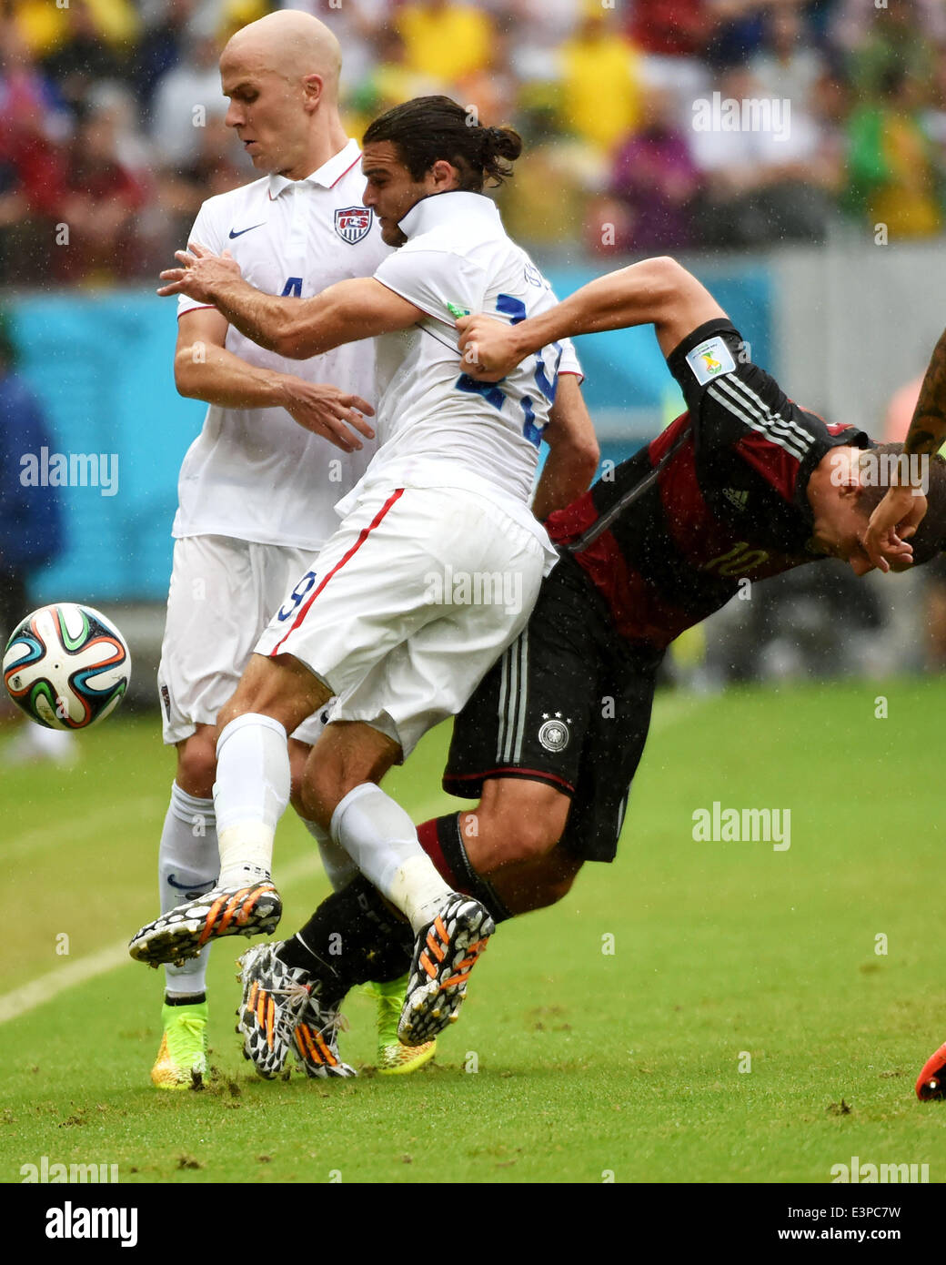 Recife, Brazil. 26th June, 2014. Germany's Lukas Podolski (R) vies with Graham Zusi (C) and Michael Bradley (L) of the U.S. during a Group G match between the U.S. and Germany of 2014 FIFA World Cup at the Arena Pernambuco Stadium in Recife, Brazil, on June 26, 2014. Credit:  Guo Yong/Xinhua/Alamy Live News Stock Photo