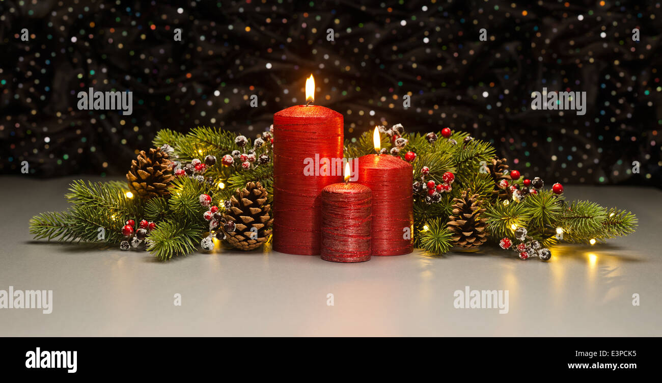 Three red Candles with Christmas tree branches and pine cones decorated Stock Photo