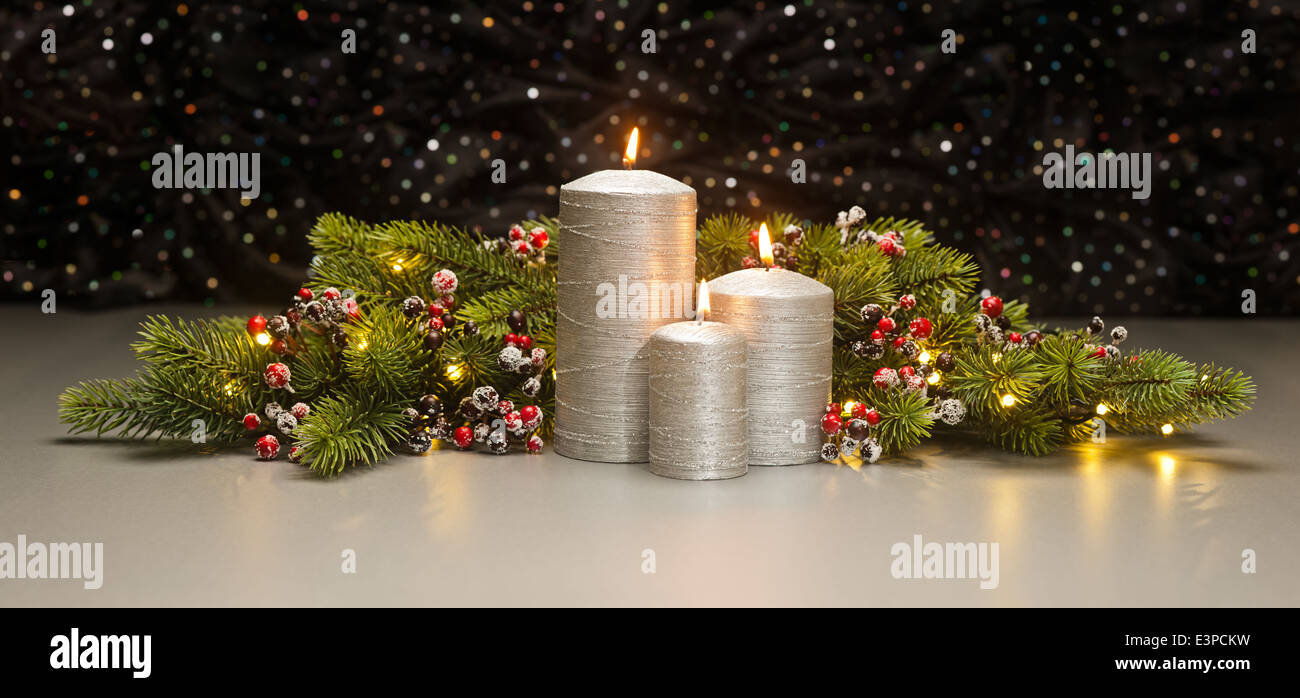 Three Silver Candles with Christmas tree branches and baubles decorated Stock Photo