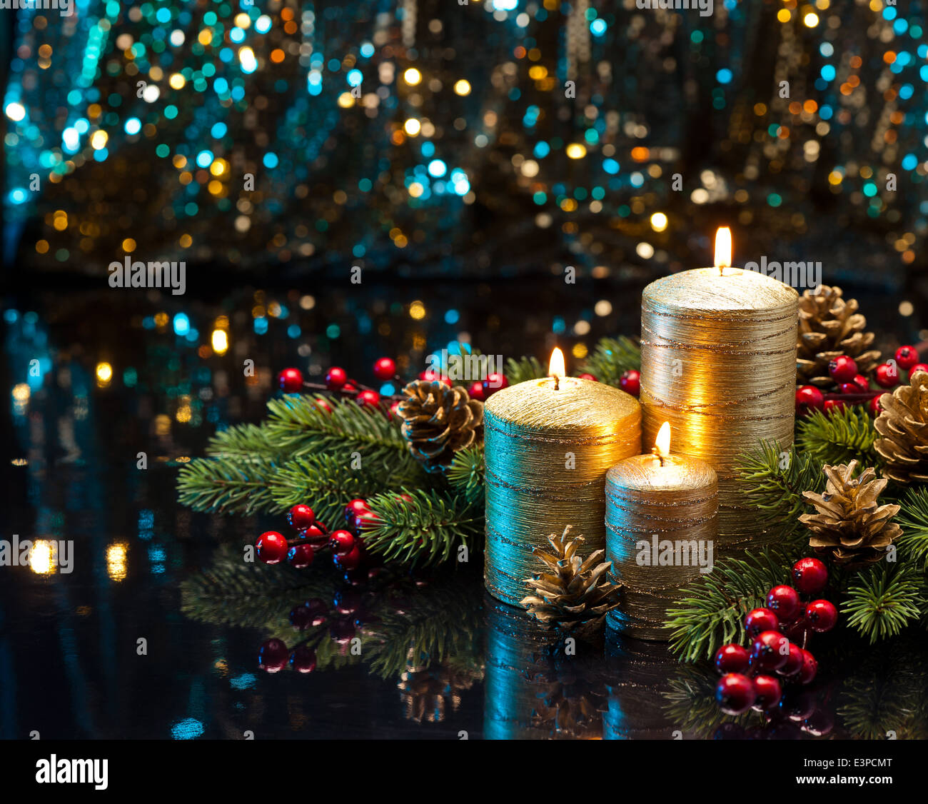 Three golden Candles with Christmas tree branches and pine cones decorated Stock Photo