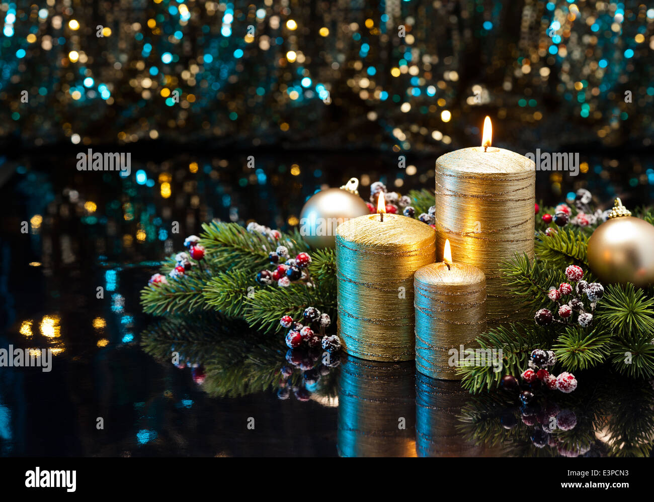 Three golden Candles with Christmas tree branches and baubles decorated Stock Photo