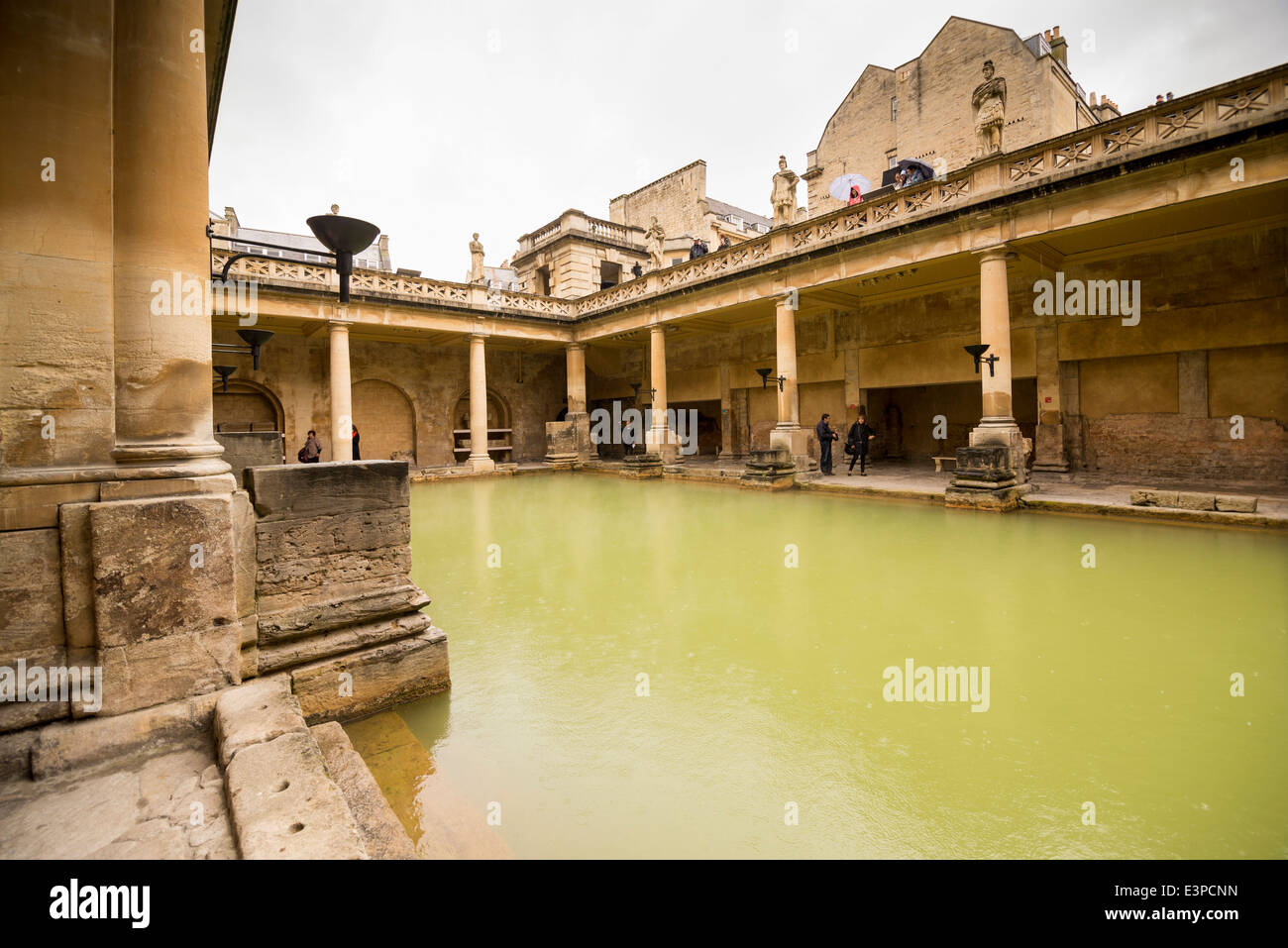 Stone and columns around the steamy water at the Roman Bath in Bath