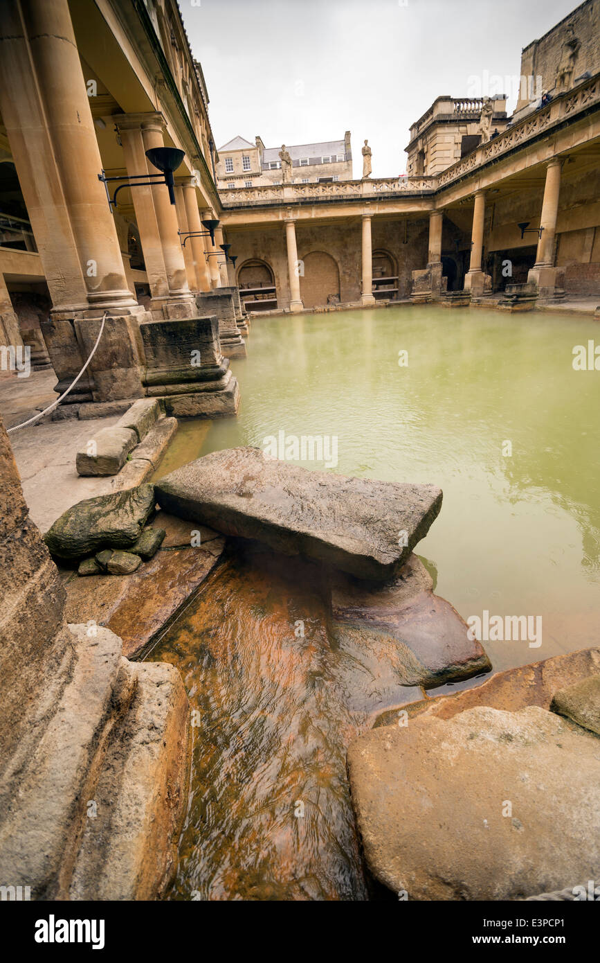 Stone and columns around the steamy water at the Roman Bath in Bath