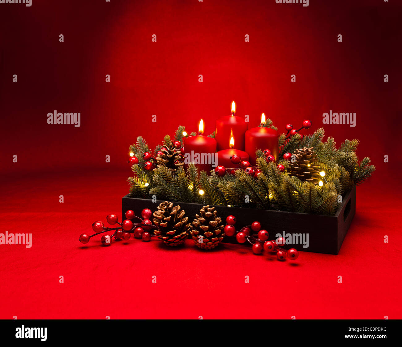 4th Advent red candle Christmas flower arrangement with berries Stock Photo