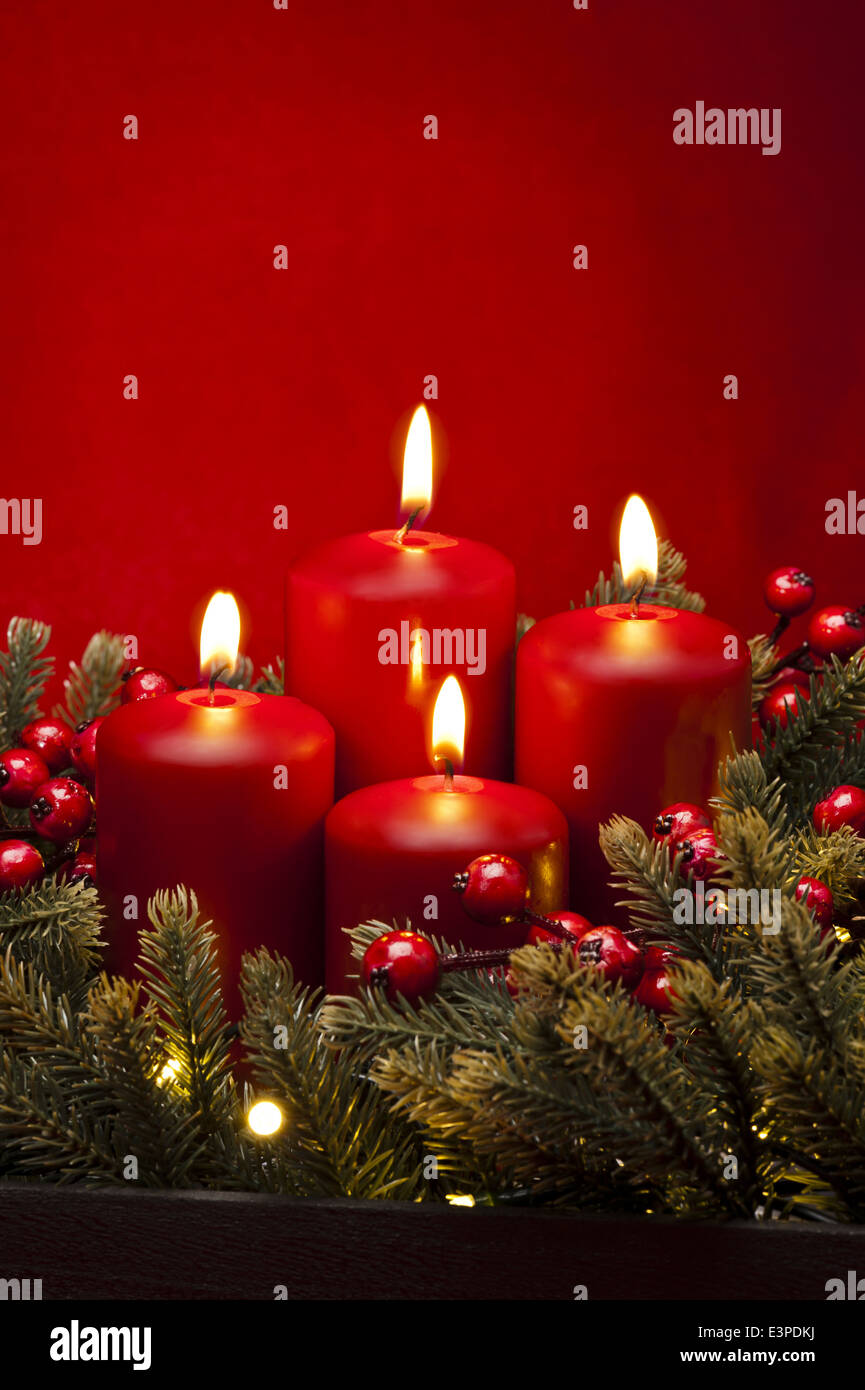 4th Advent red candle Christmas flower arrangement with berries Stock Photo
