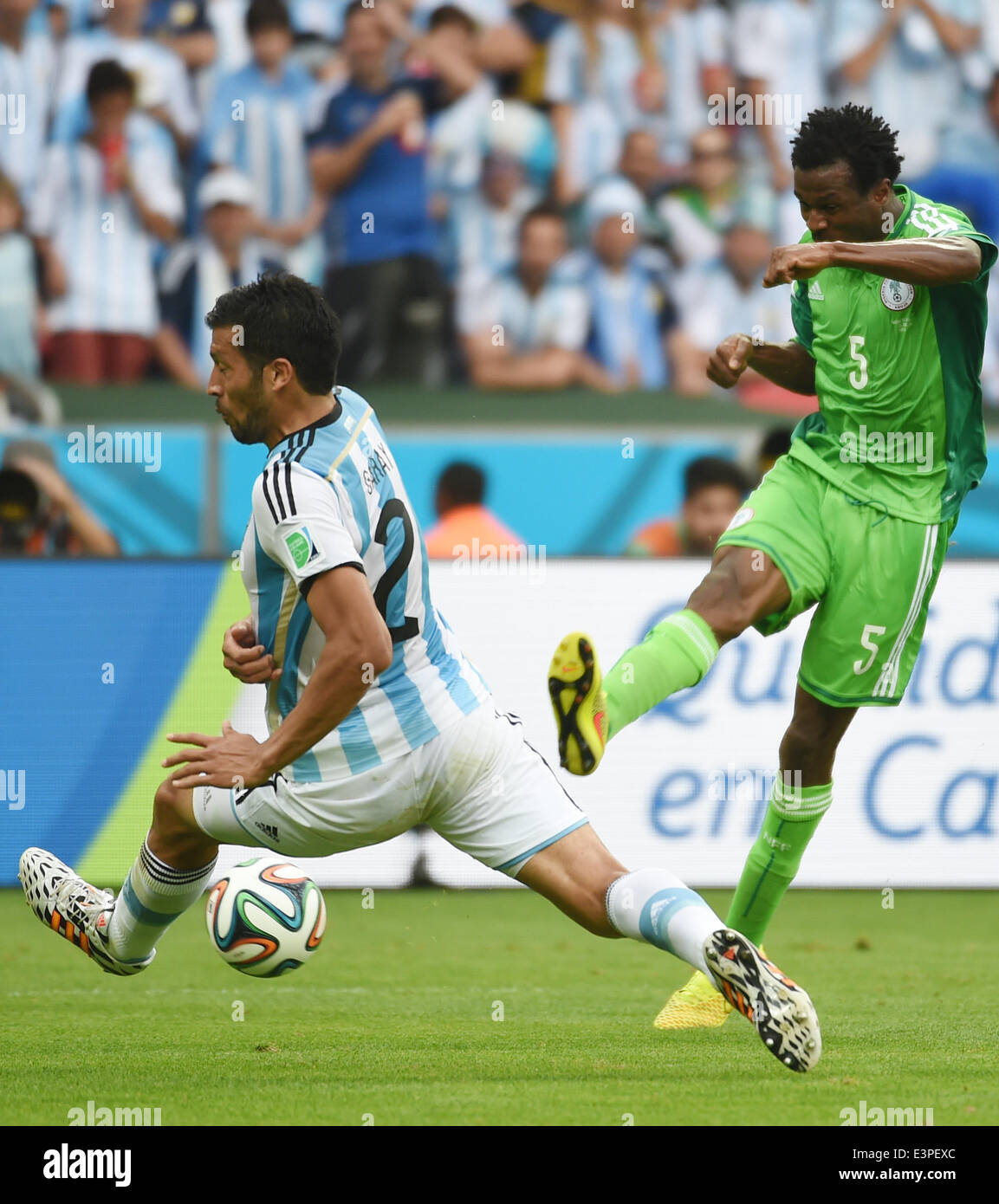 Porto Alegre, Brazil. 25th June, 2014. Argentina's Ezequiel Garay (L) attempts to block a shot by Nigeria's Efe Ambrose during a Group F match between Nigeria and Argentina of 2014 FIFA World Cup at the Estadio Beira-Rio Stadium in Porto Alegre, Brazil, on June 25, 2014. Argentina won 3-2 over Nigeria on Wednesday. © Li Ga/Xinhua/Alamy Live News Stock Photo