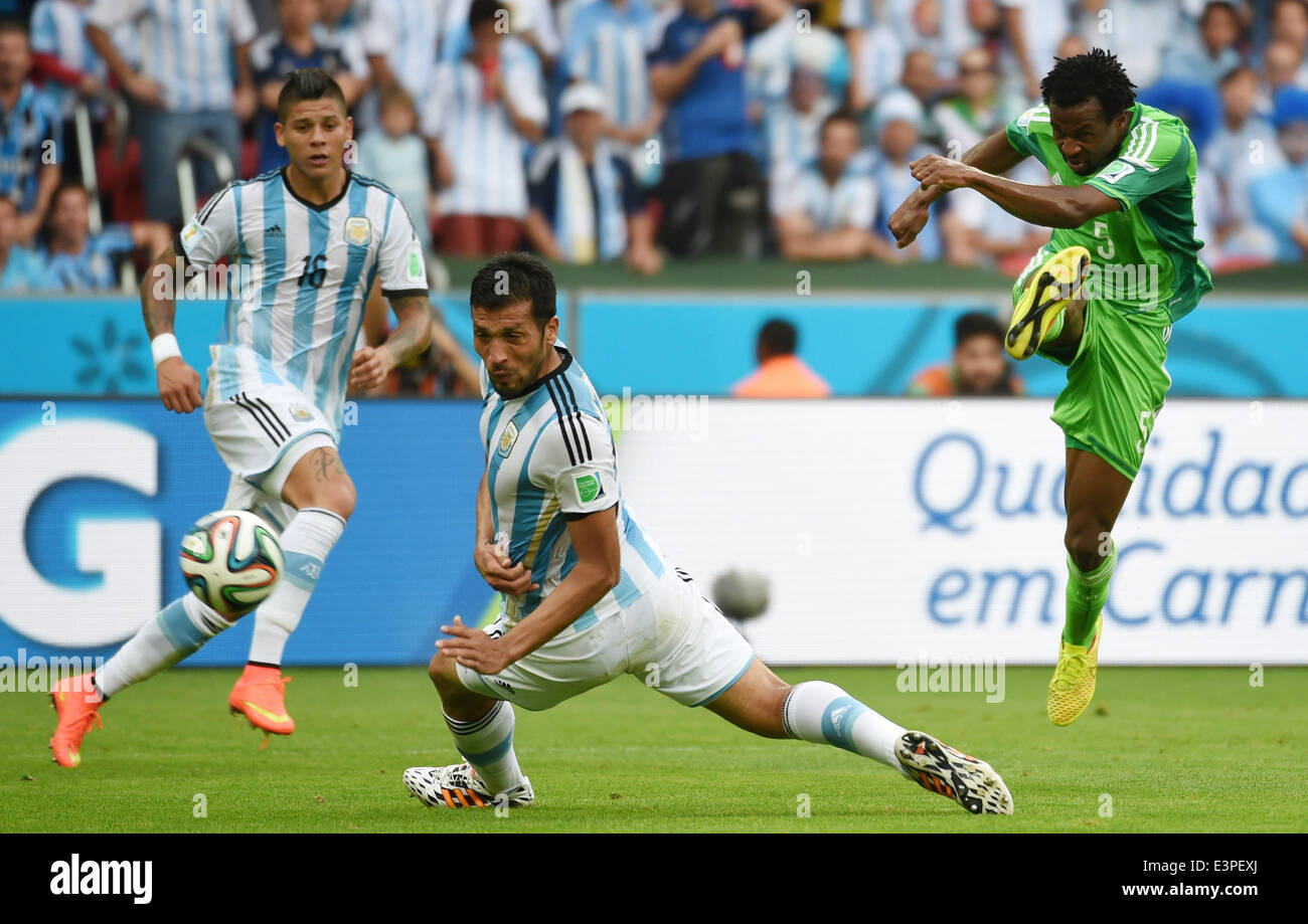 Porto Alegre, Brazil. 25th June, 2014. Argentina's Ezequiel Garay (C) fails to block a shot by Nigeria's Efe Ambrose (R) during a Group F match between Nigeria and Argentina of 2014 FIFA World Cup at the Estadio Beira-Rio Stadium in Porto Alegre, Brazil, on June 25, 2014. Argentina won 3-2 over Nigeria on Wednesday. © Li Ga/Xinhua/Alamy Live News Stock Photo