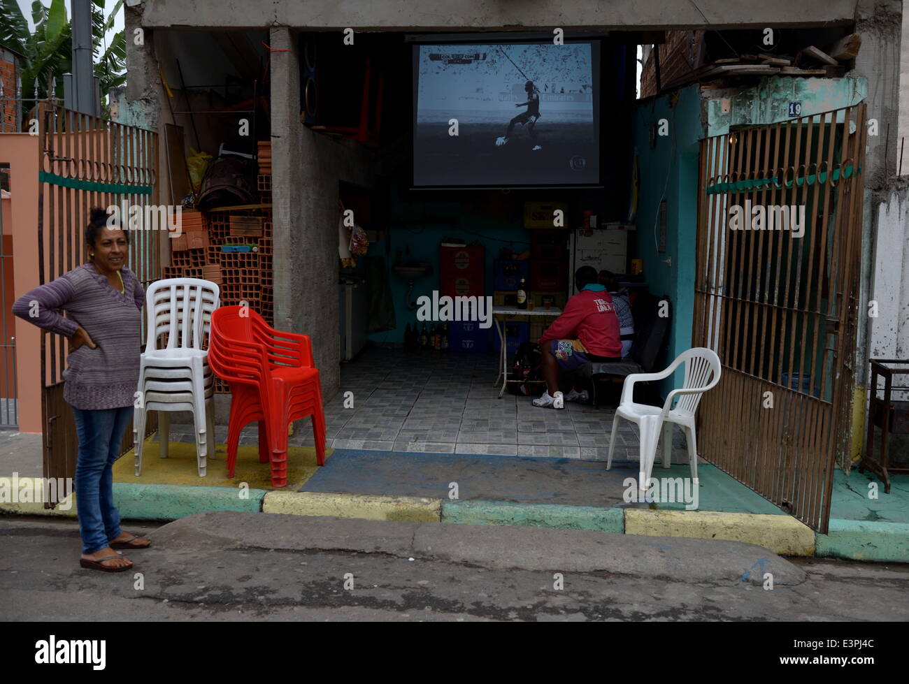 Sao Paulo, Brazil. 19th June, 2014. Brazilians are watching a worldcup game over a screen in the garage of a house at Itaquera, a suburb of Sao Paulo on June 19, 2014.More than a million Brazilians took to the streets a year ago to protest government spending on the tournament. The country's economy has slowed to a crawl and public education and health care lag behind those of industrialized nations. Polls show that most Brazilians think hosting the World Cup was a bad idea. © Gili Yaari/NurPhoto/ZUMAPRESS.com/Alamy Live News Stock Photo