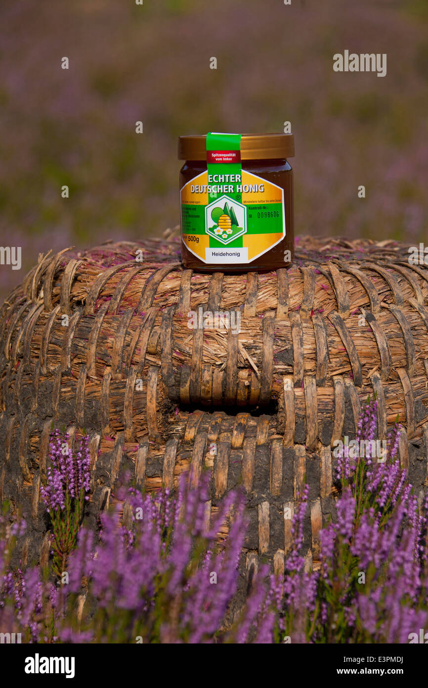 Tradional bee hives (skeps) made from straw with a glass of honey. Lueneburg Heath, Lower Saxony, Germany Stock Photo