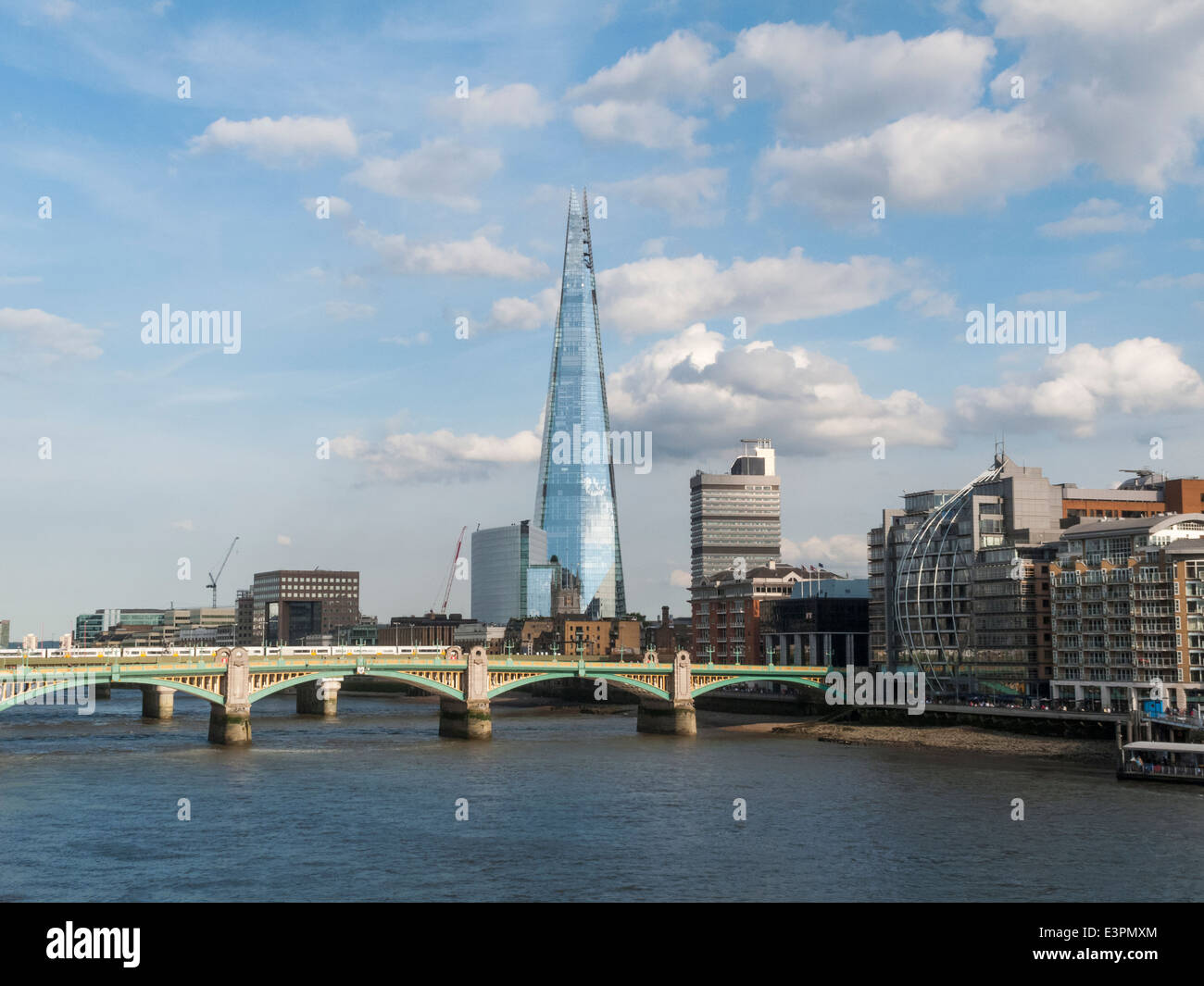 London city skyline with The Shard, Southwark Bridge and the River Thames, in summer with blue sky and white fluffy clouds Stock Photo