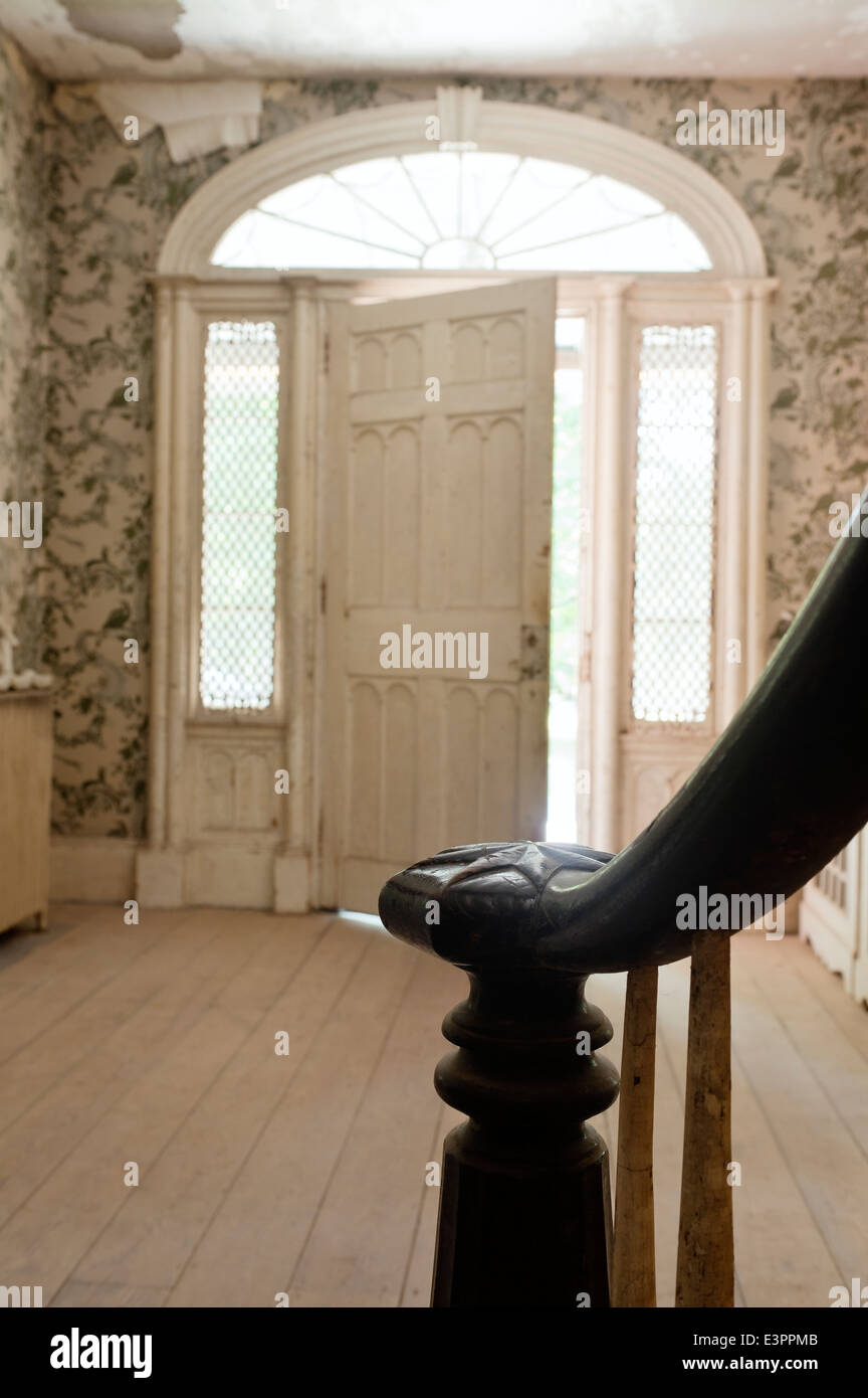 Detail of balustrade in entrance hall with semi-elliptical front door and patterned wallpaper Stock Photo