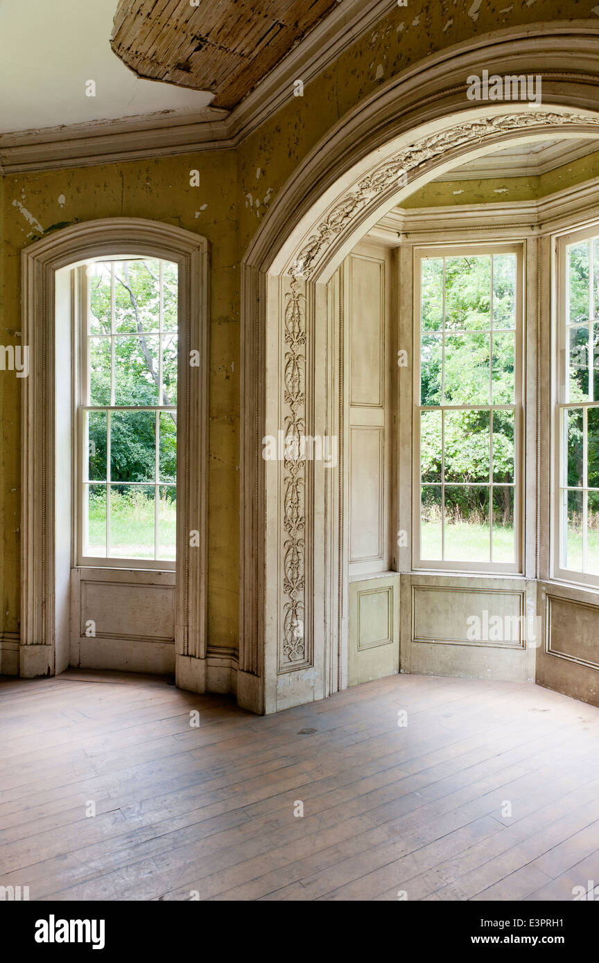 tripartite window in empty room with peeling wallpaper and damaged ceiling Stock Photo