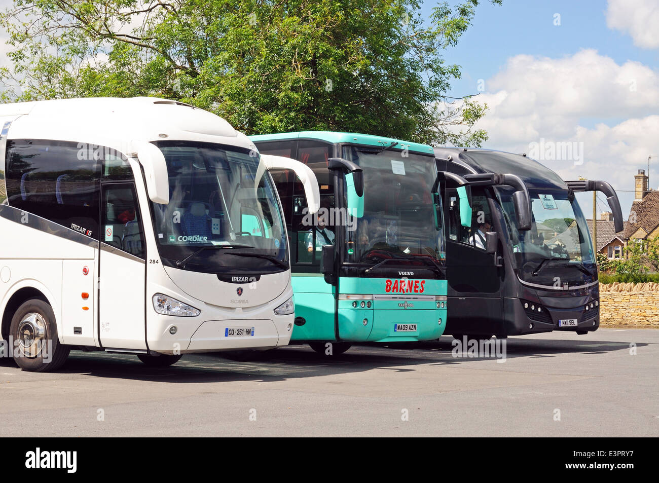 Three tourist coaches parked in a row in a coach and car park, Bourton