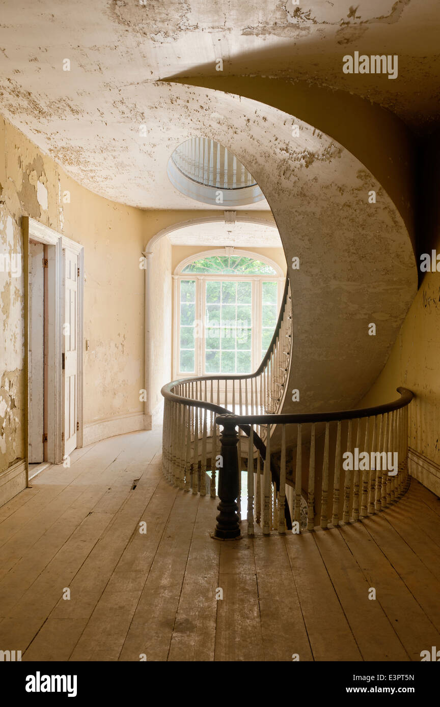 Elliptical staircase on first floor landing with cracked and peeling wall paint Stock Photo