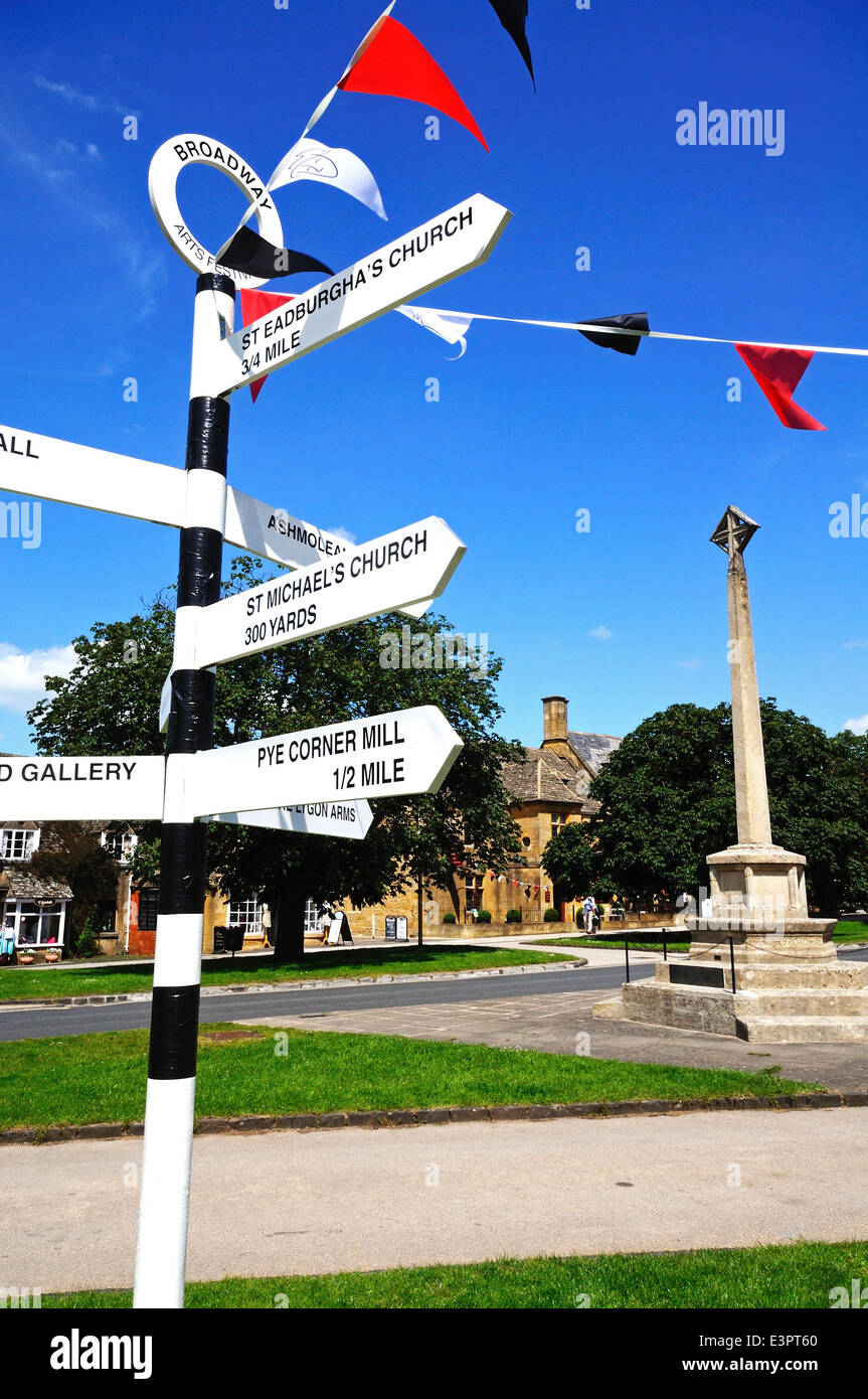 Black and white signpost on the village green along the High Street giving directions to tourist attractions, Broadway, England. Stock Photo