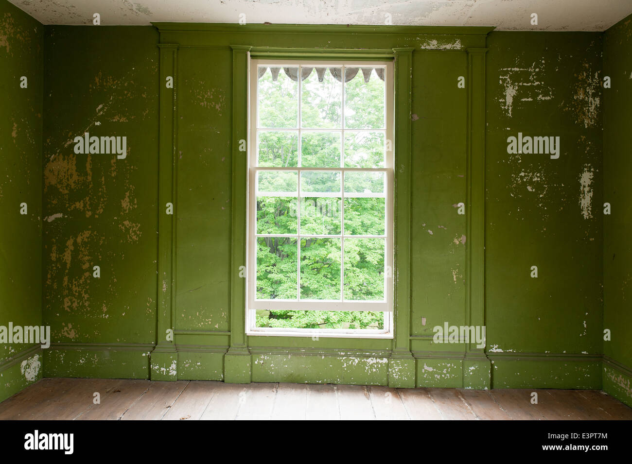 Peeling green wall paint in empty room with open window Stock Photo
