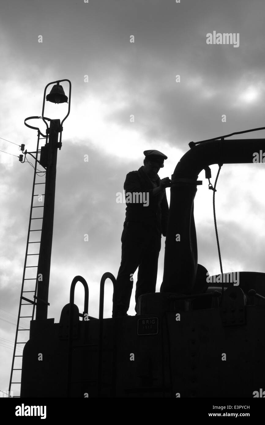The Fireman of a Steam Train filling up with water Stock Photo