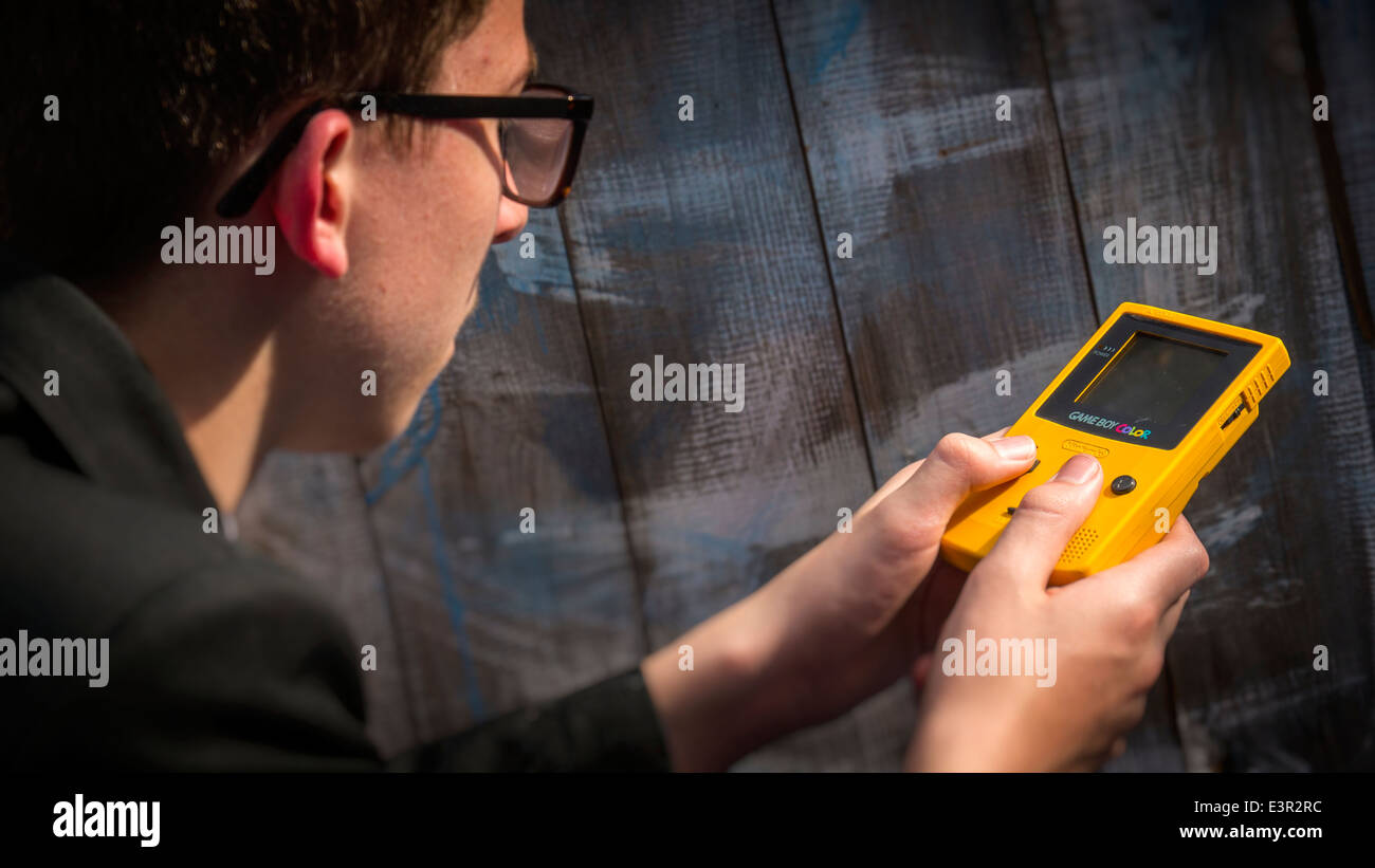 School Teenager Playing on a Nintendo Game Boy Color. Stock Photo