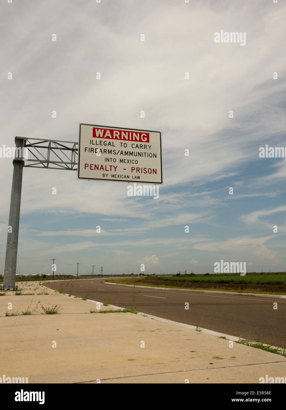 Large sign warns that it is illegal to carry firearms and ammunition into Mexico stating that penalty is prison by Mexican law. Stock Photo
