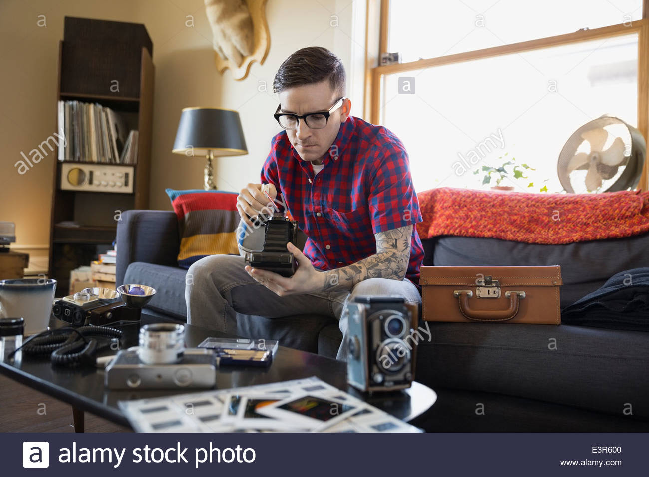 Man repairing antique camera in living room Stock Photo