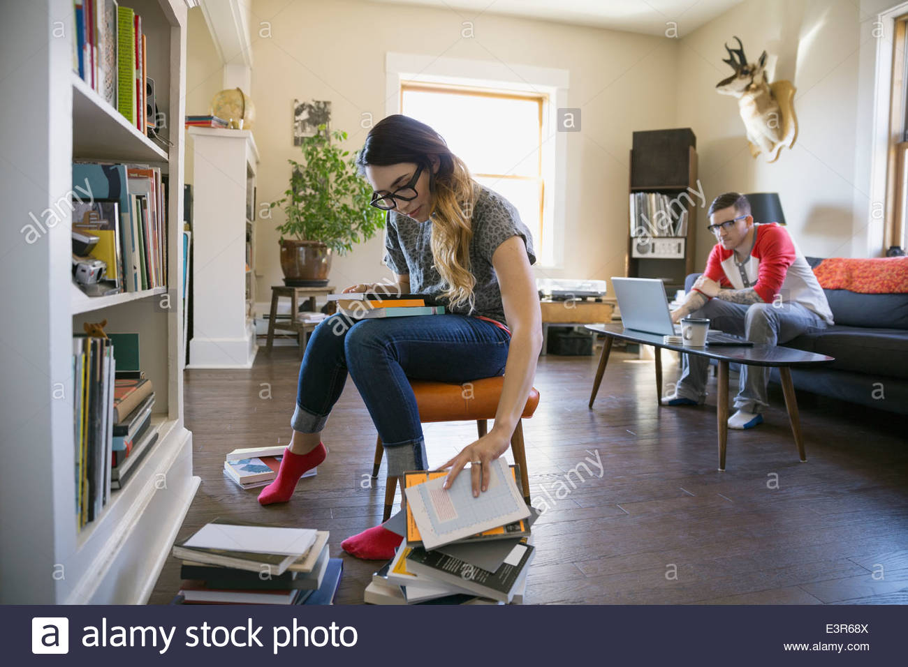 Woman sorting through books in bookcase Stock Photo