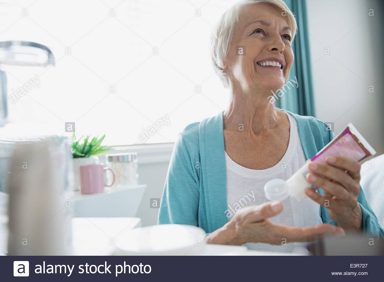 Woman applying moisturizer Stock Photo