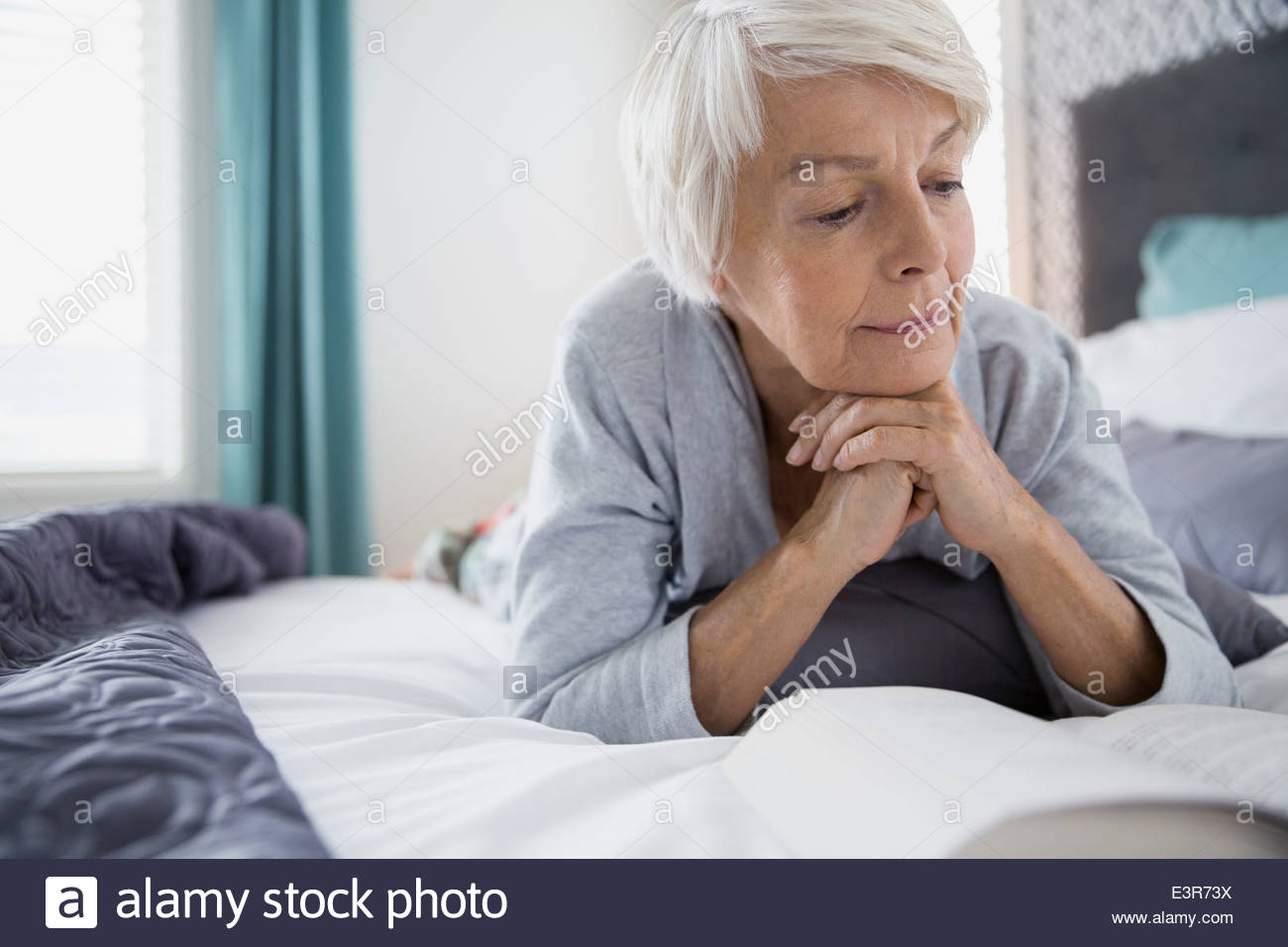 Woman reading book in bed Stock Photo