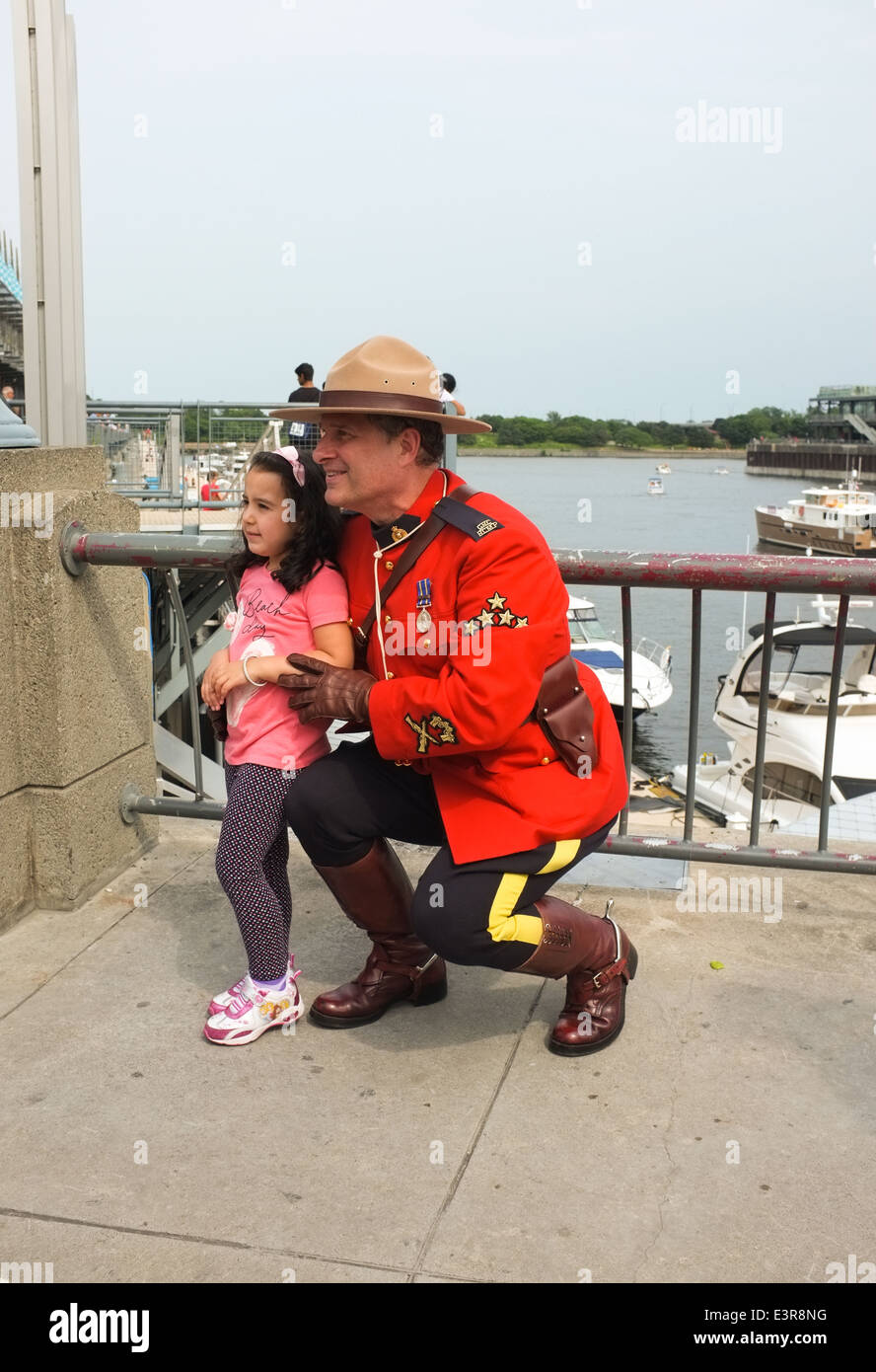 A young child has her photo taken with an RCMP officer in uniform during Canada Day celebrations in the Old Port of Montreal, Qu Stock Photo