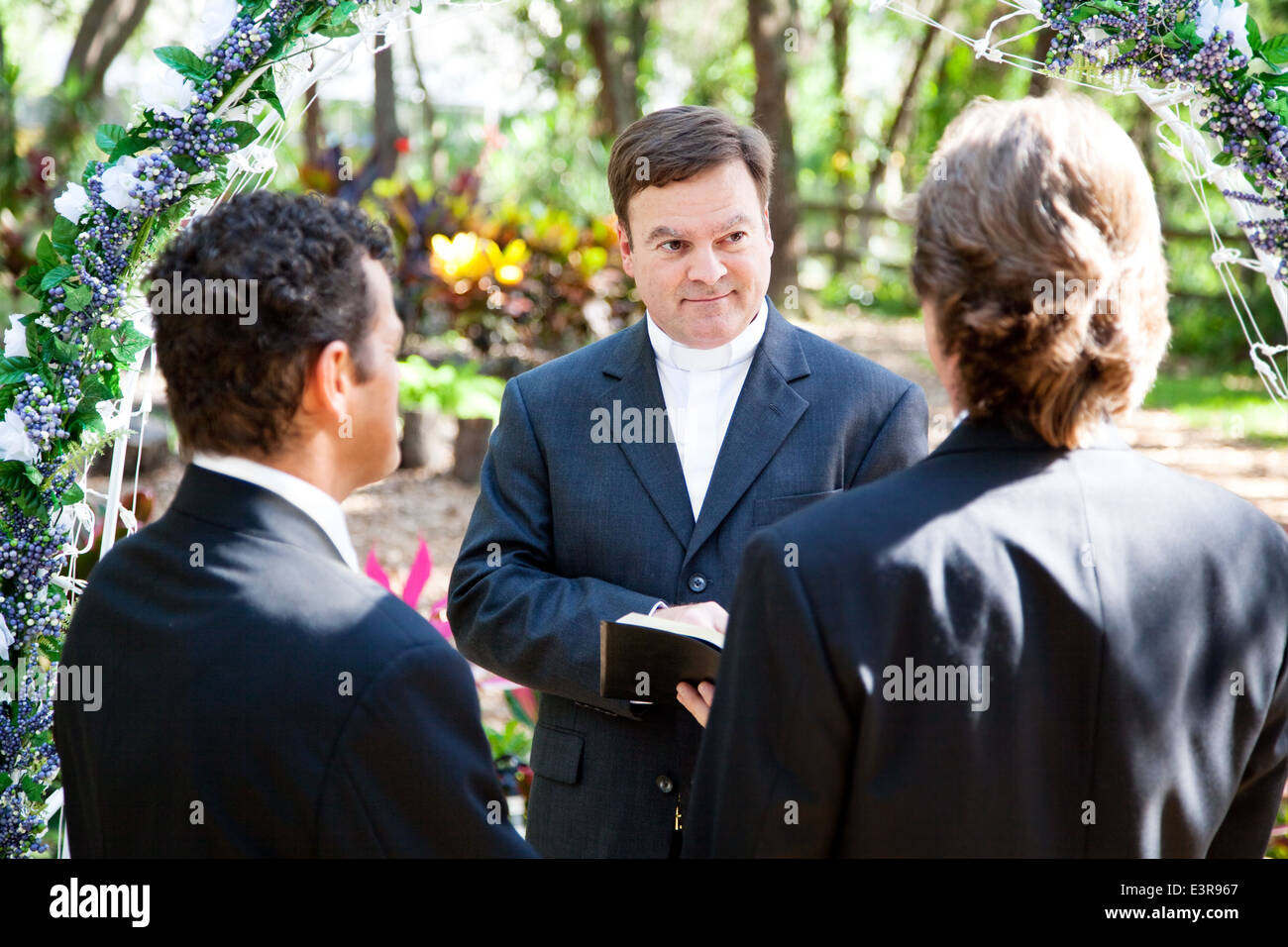 Minister performing marriage ceremony for two grooms at a gay wedding.  Stock Photo
