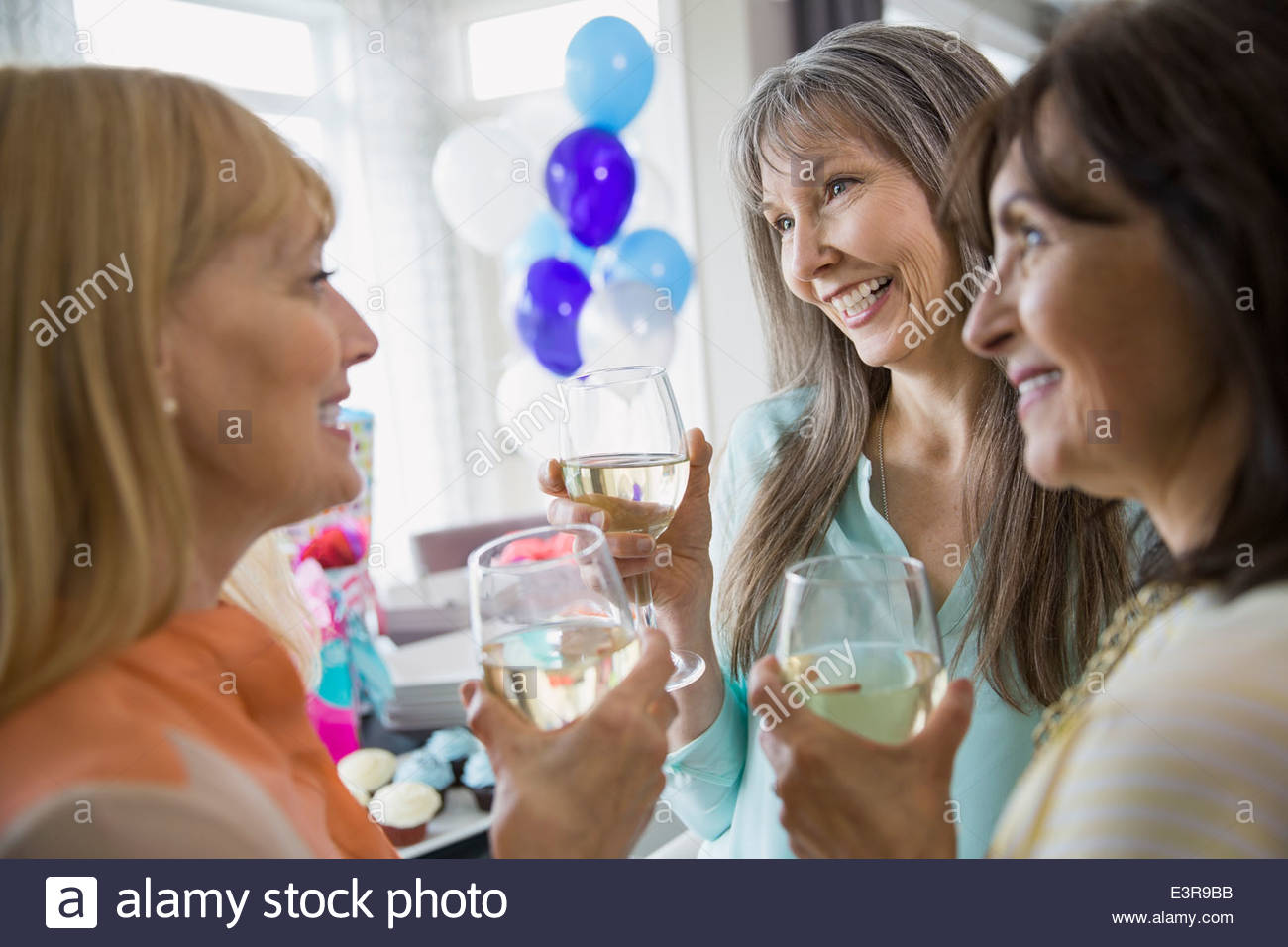 Women talking and drinking white wine at party Stock Photo