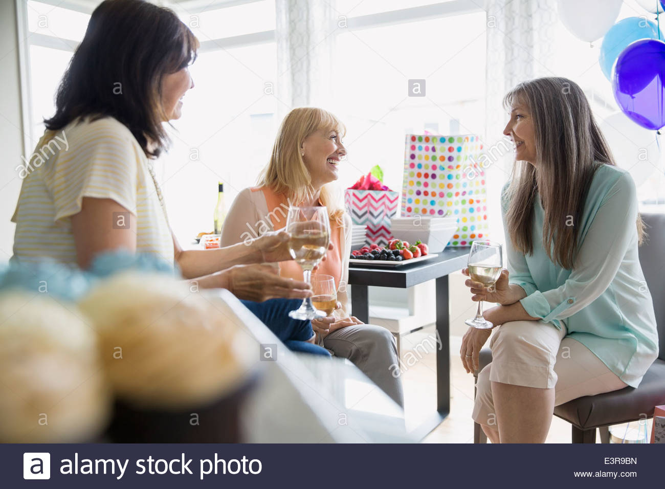 Women talking and drinking white wine at party Stock Photo