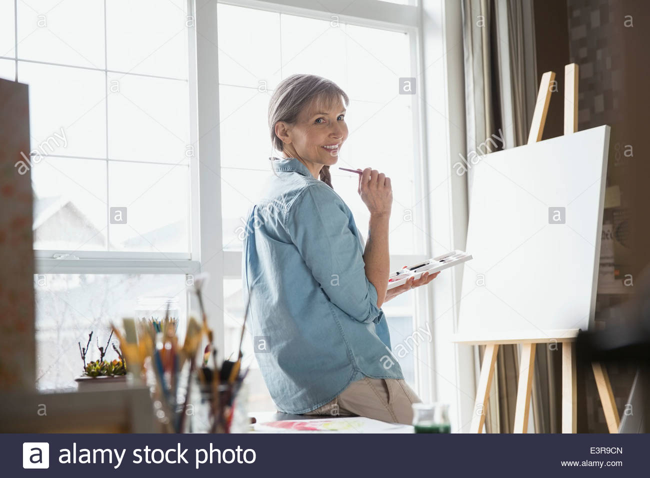 Portrait of woman painting at easel Stock Photo