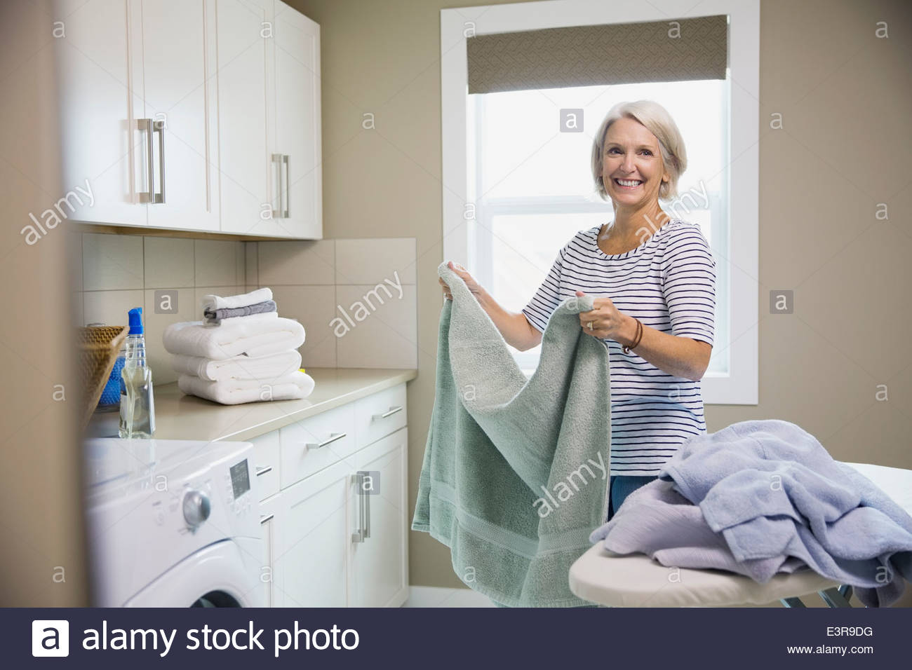 Smiling woman folding laundry in laundry room Stock Photo Alamy