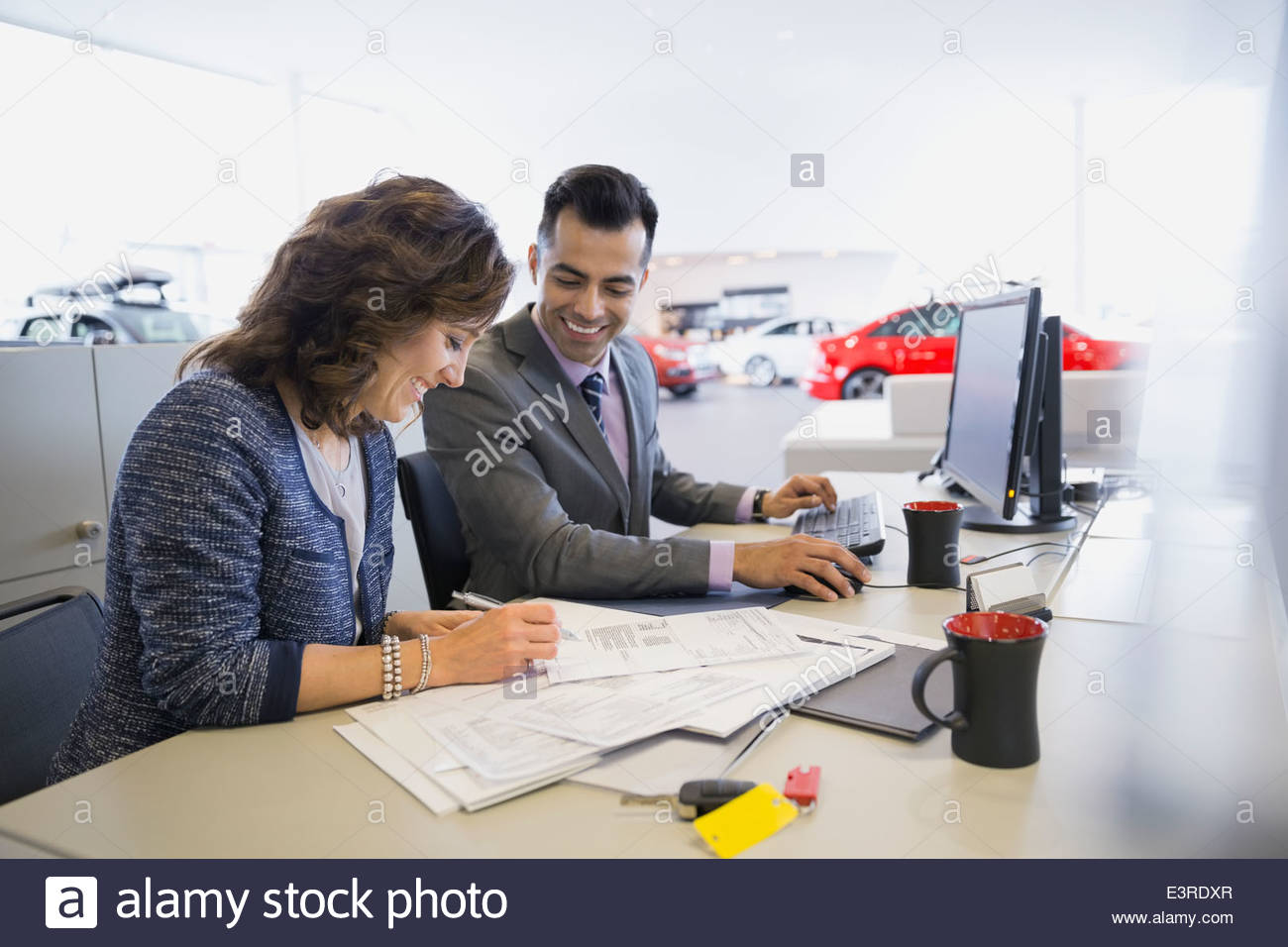 Salesman and woman finalizing paperwork in car dealership Stock Photo