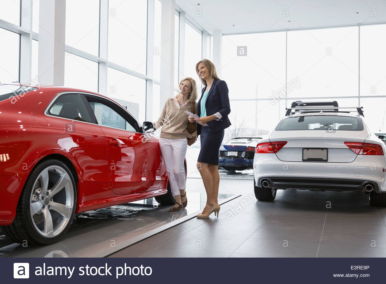 Saleswoman and woman looking at car in showroom Stock Photo