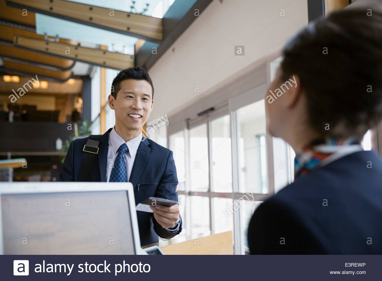 Businessman checking in at airport counter Stock Photo - Alamy