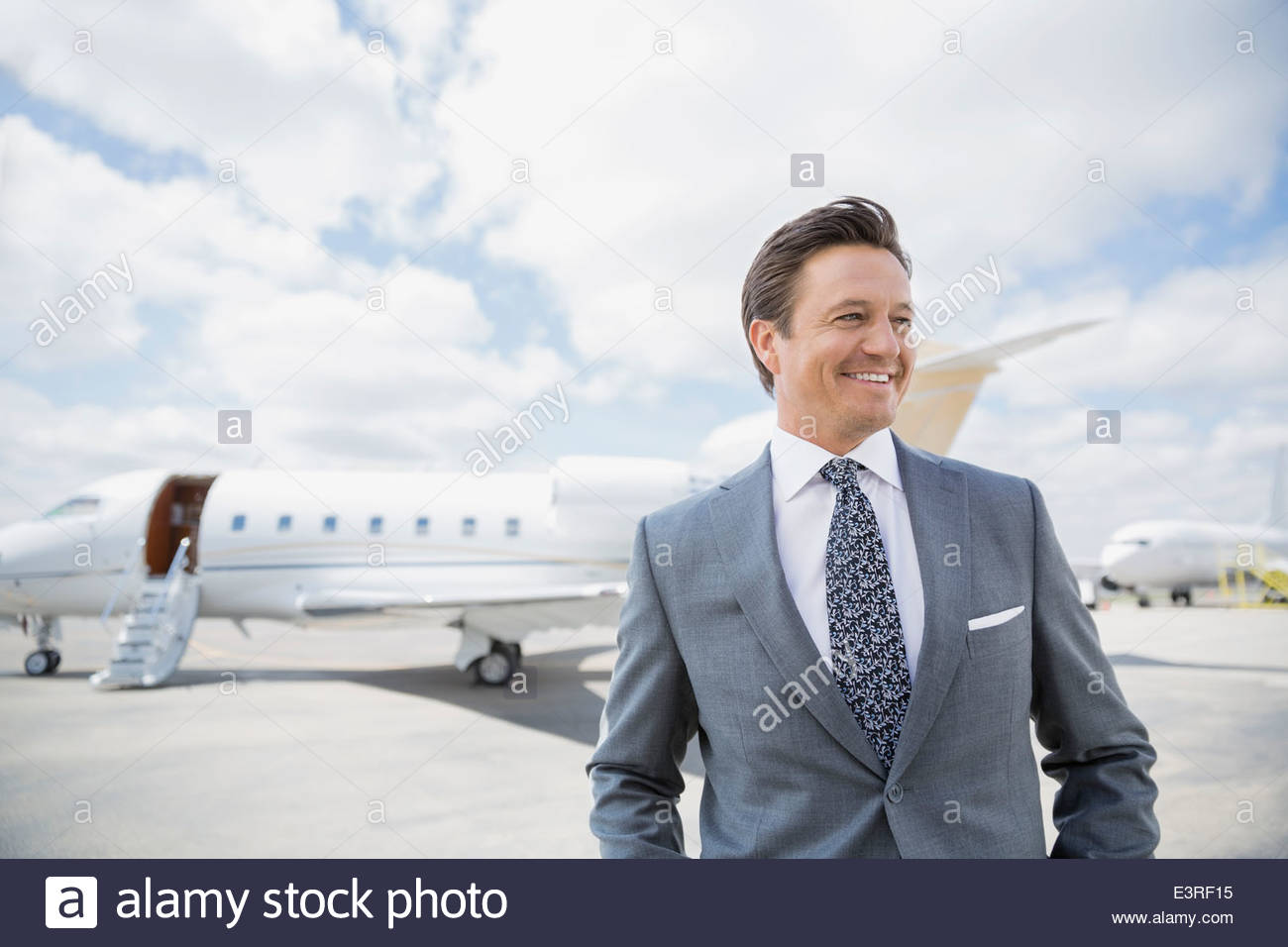 Businessman on tarmac with corporate jet Stock Photo
