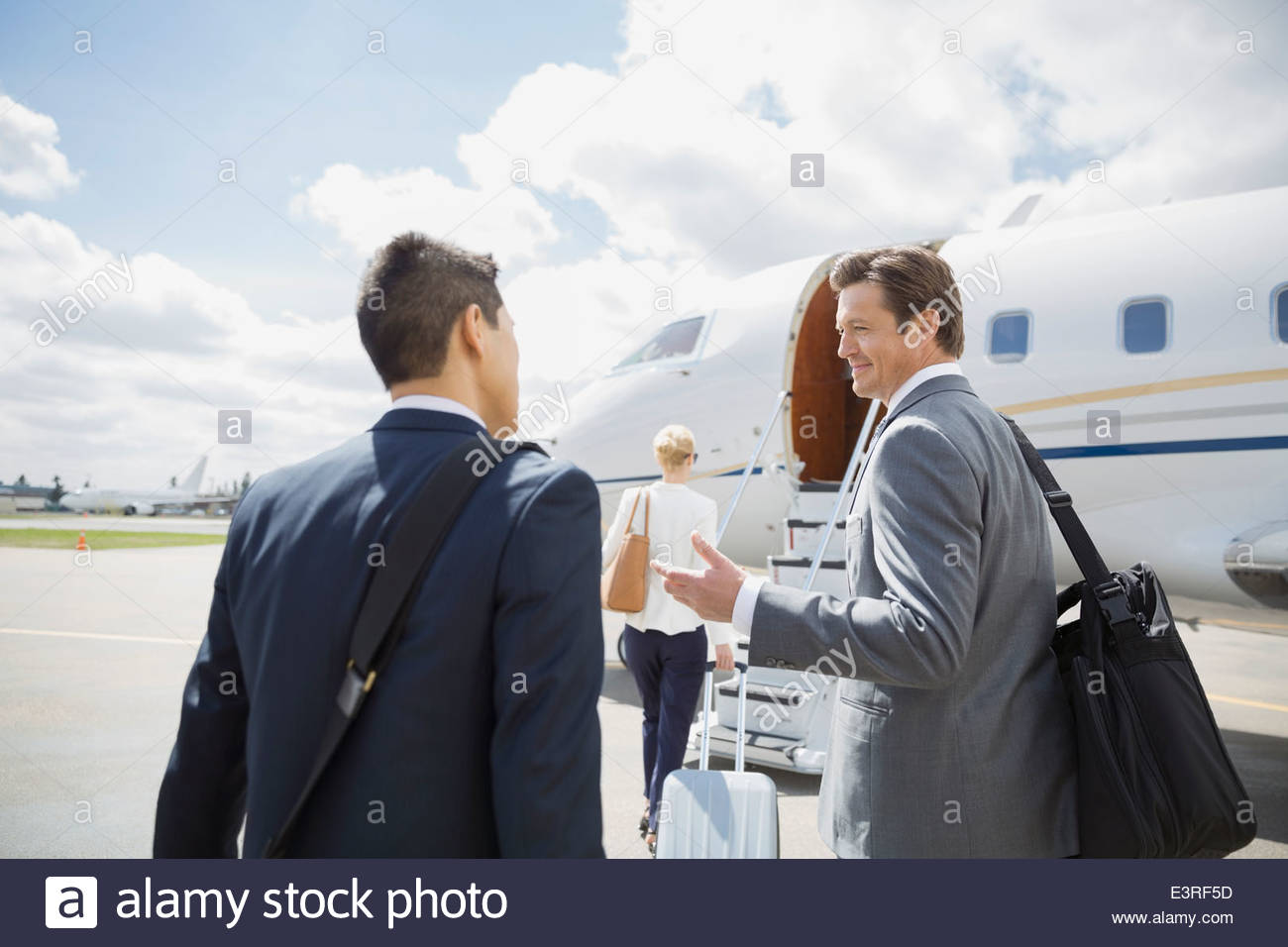 Businessmen talking on tarmac with corporate jet Stock Photo