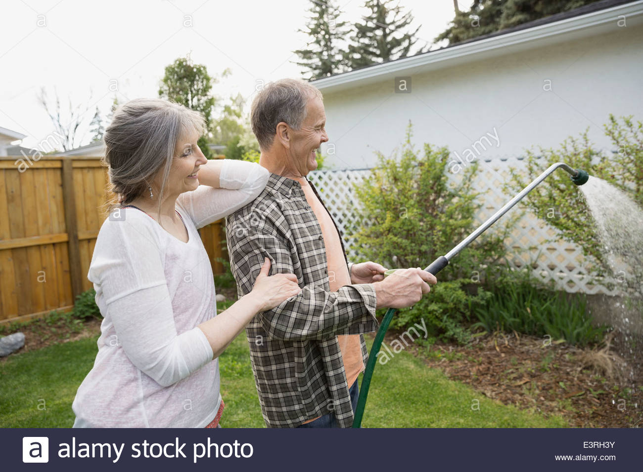 Senior couple watering plants in garden Stock Photo