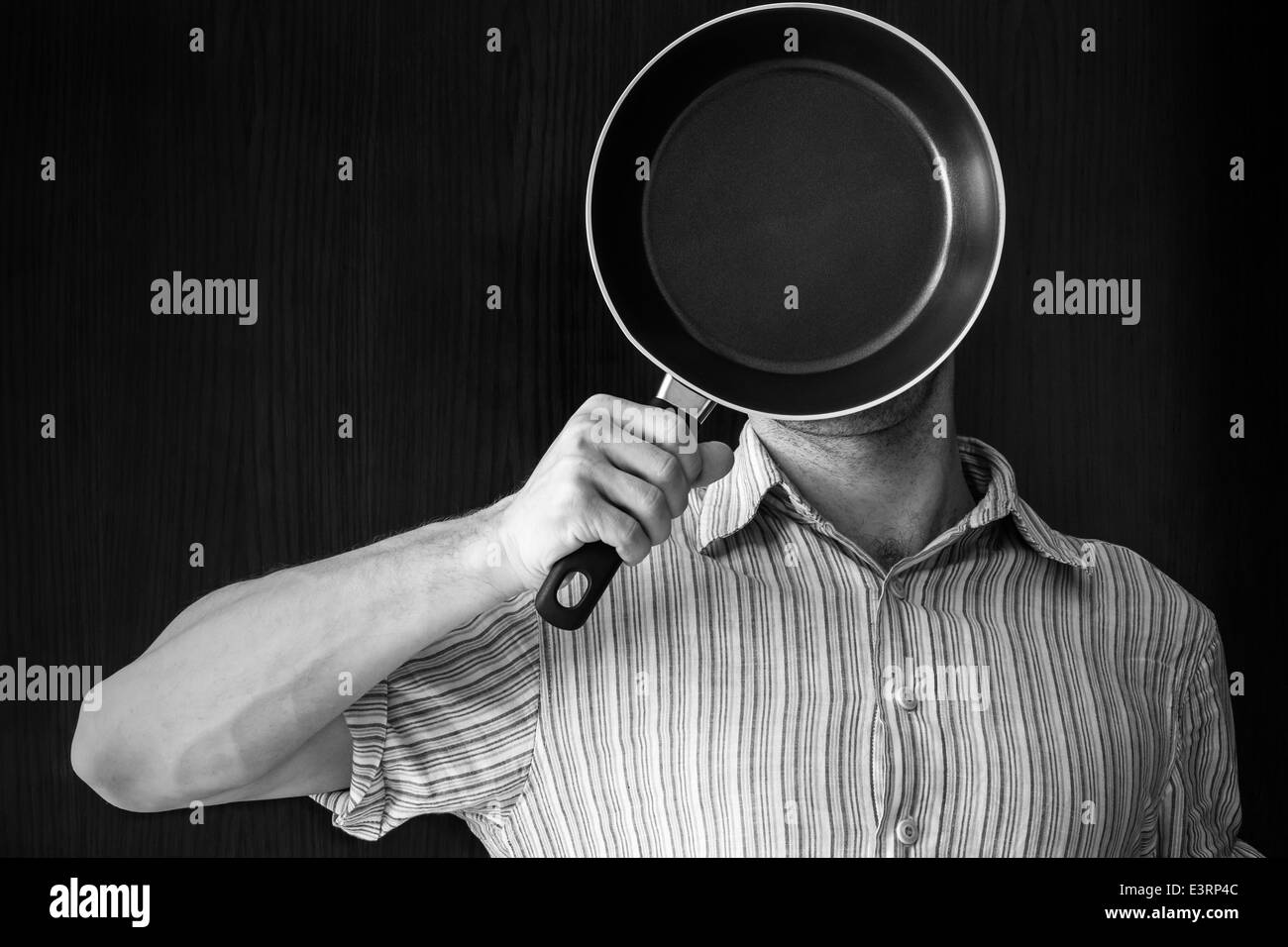 Young man monochrome portrait behind black frying pan Stock Photo