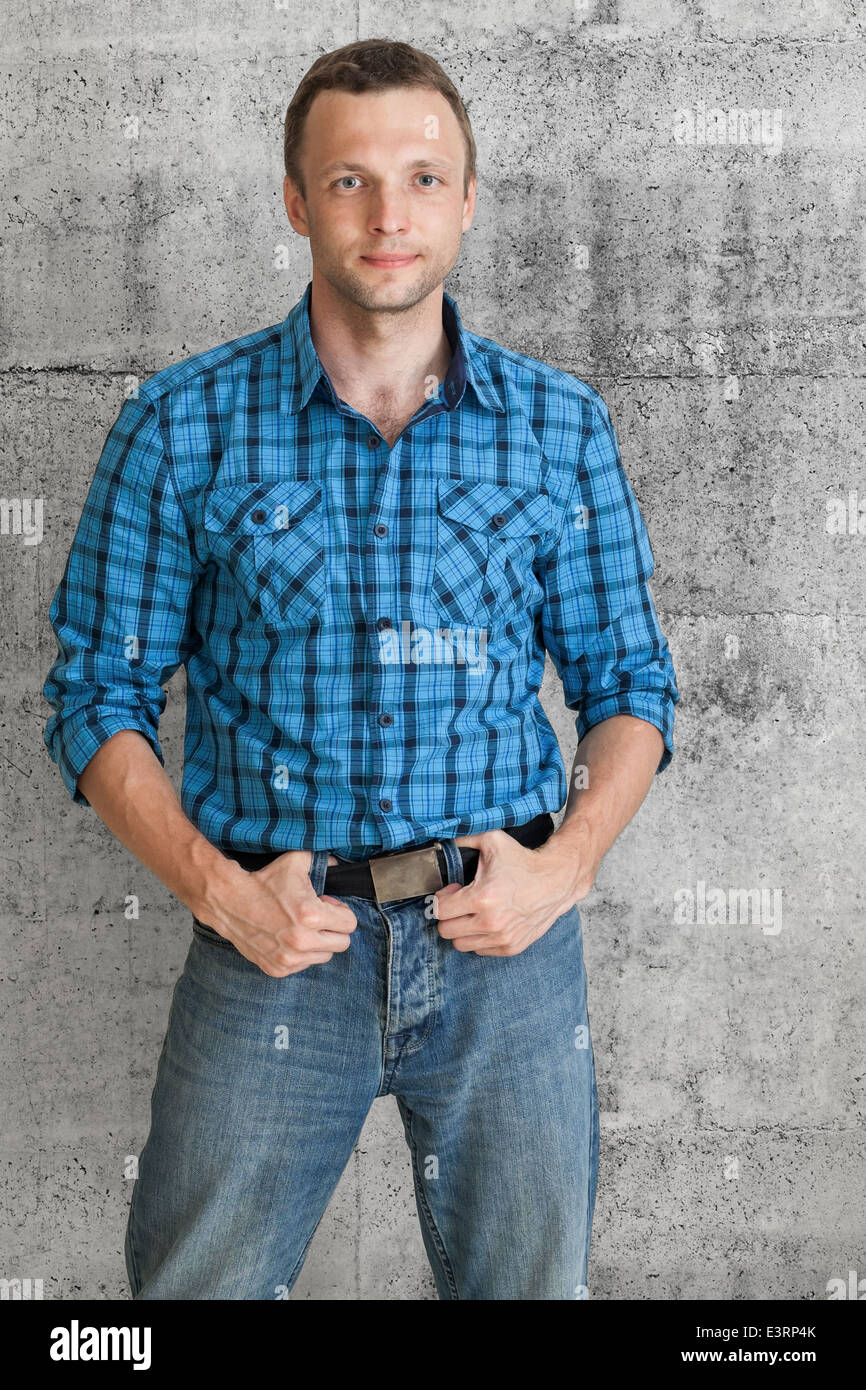 Young Caucasian man in blue shirt above concrete wall Stock Photo