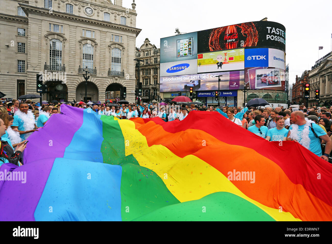London, UK. 28th June 2014. Giant rainbow flag at Piccadilly Circus at the Pride London Parade 2014 in London. Rain storms throughout the day didn't dampen the spirits of the 20,000 people in the parade of the crowds in the packed streets watching. It did however bring out plenty of rainbow umbrellas. Credit:  Paul Brown/Alamy Live News Stock Photo