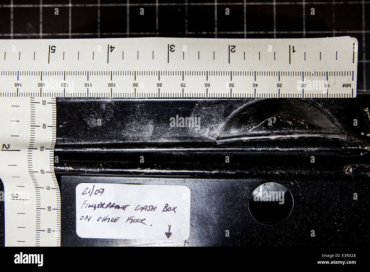 Crime scene examination of a cash tin with aluminium powder showing enhanced fingerprints in the silver power Stock Photo