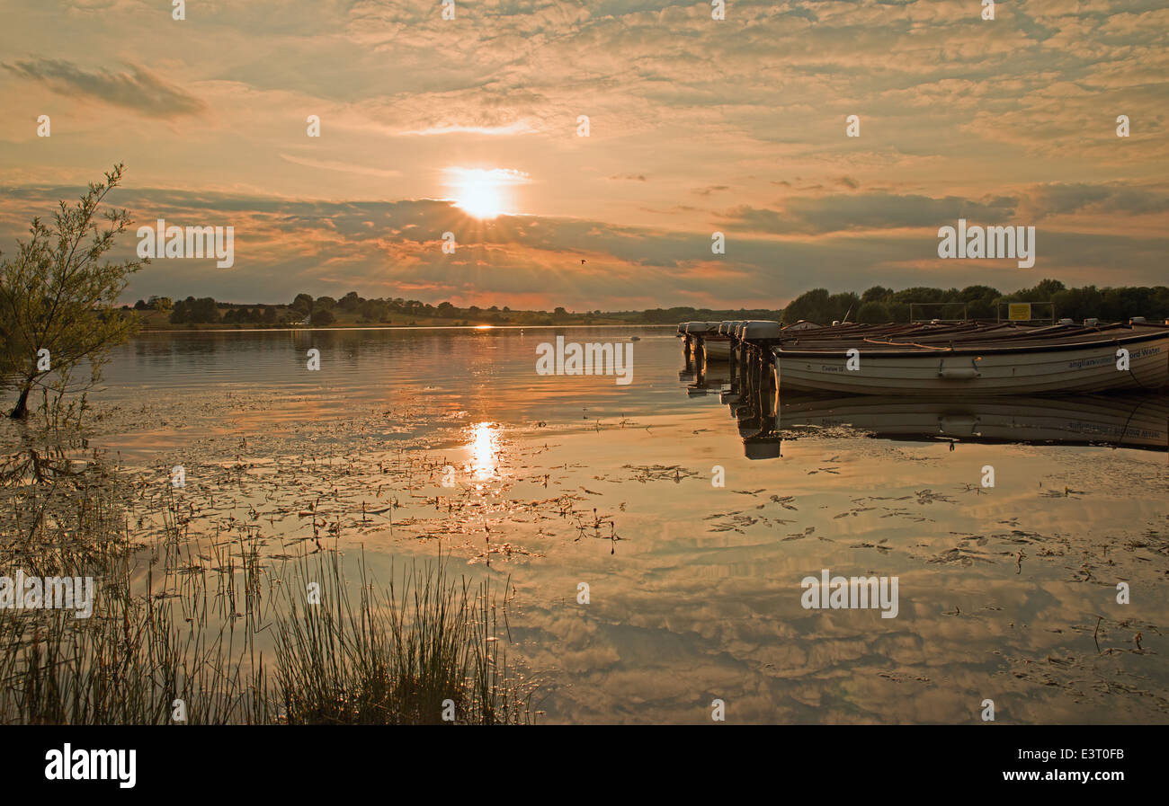 Twilight Scene with fishing Boats and Sun reflecting off of water at Pitsford  Reservoir Northamptonshire Stock Photo