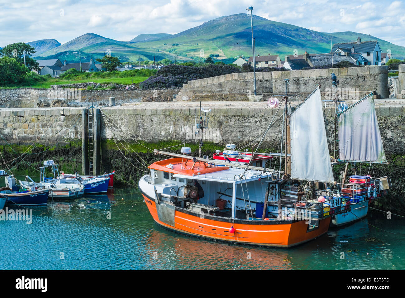 Fishing boats in Annalong Harbour with the Mourne Mountains in the background on a sunny peaceful evening. Stock Photo