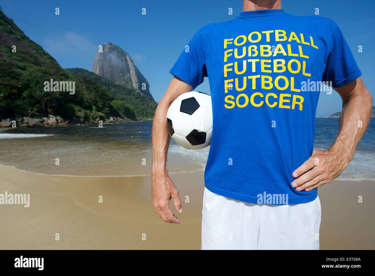 International football player in multi language message t-shirt holding football Red Beach Rio de Janeiro Brazil Stock Photo