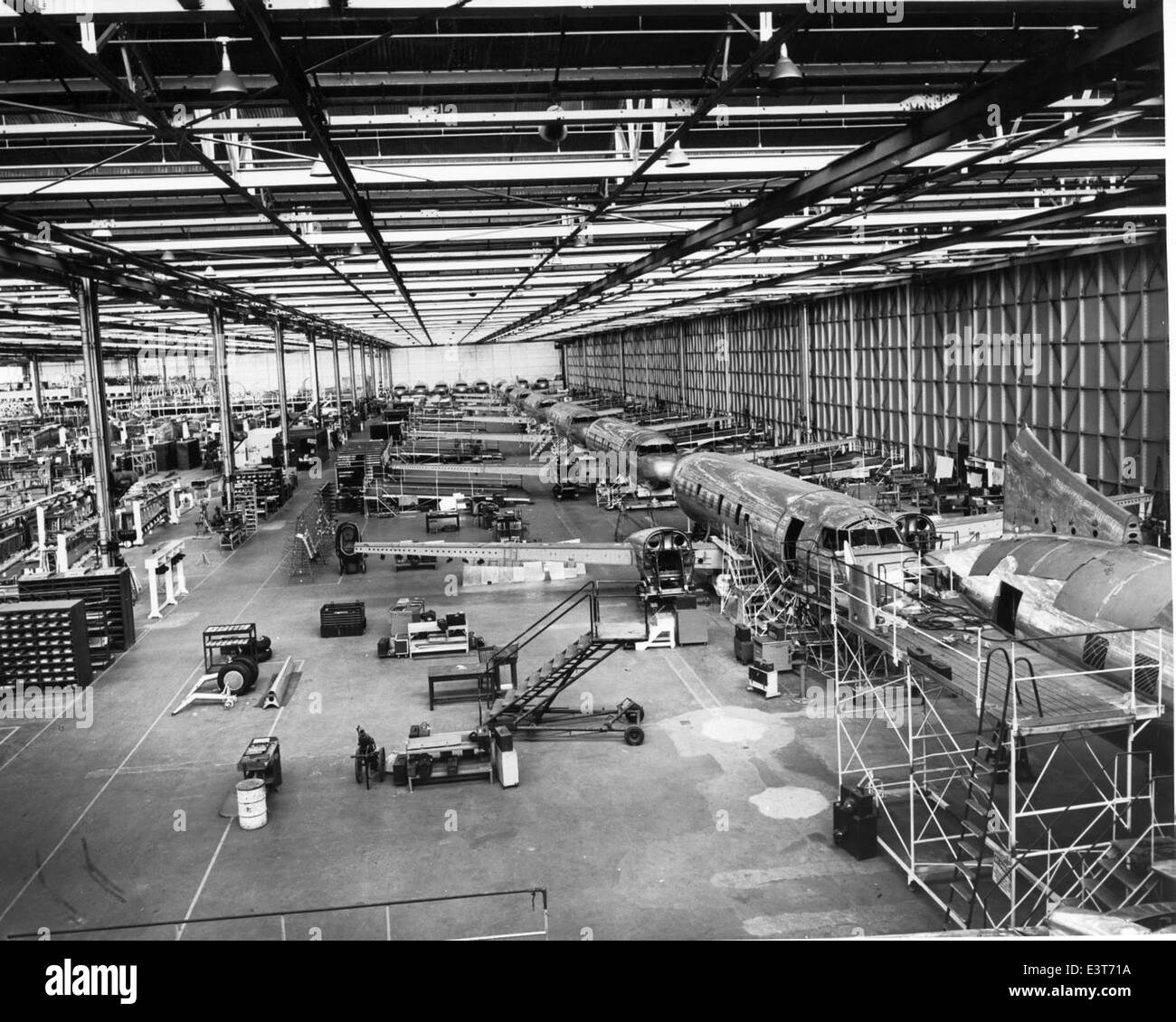 The Convair 240, an airliner developed in 1948, was powered by Pratt & Whitney R-2800 engines and used by various airlines for regional flights. The production line shown in the image highlights the mass production and efficiency in aircraft manufacturing during this period. Stock Photo