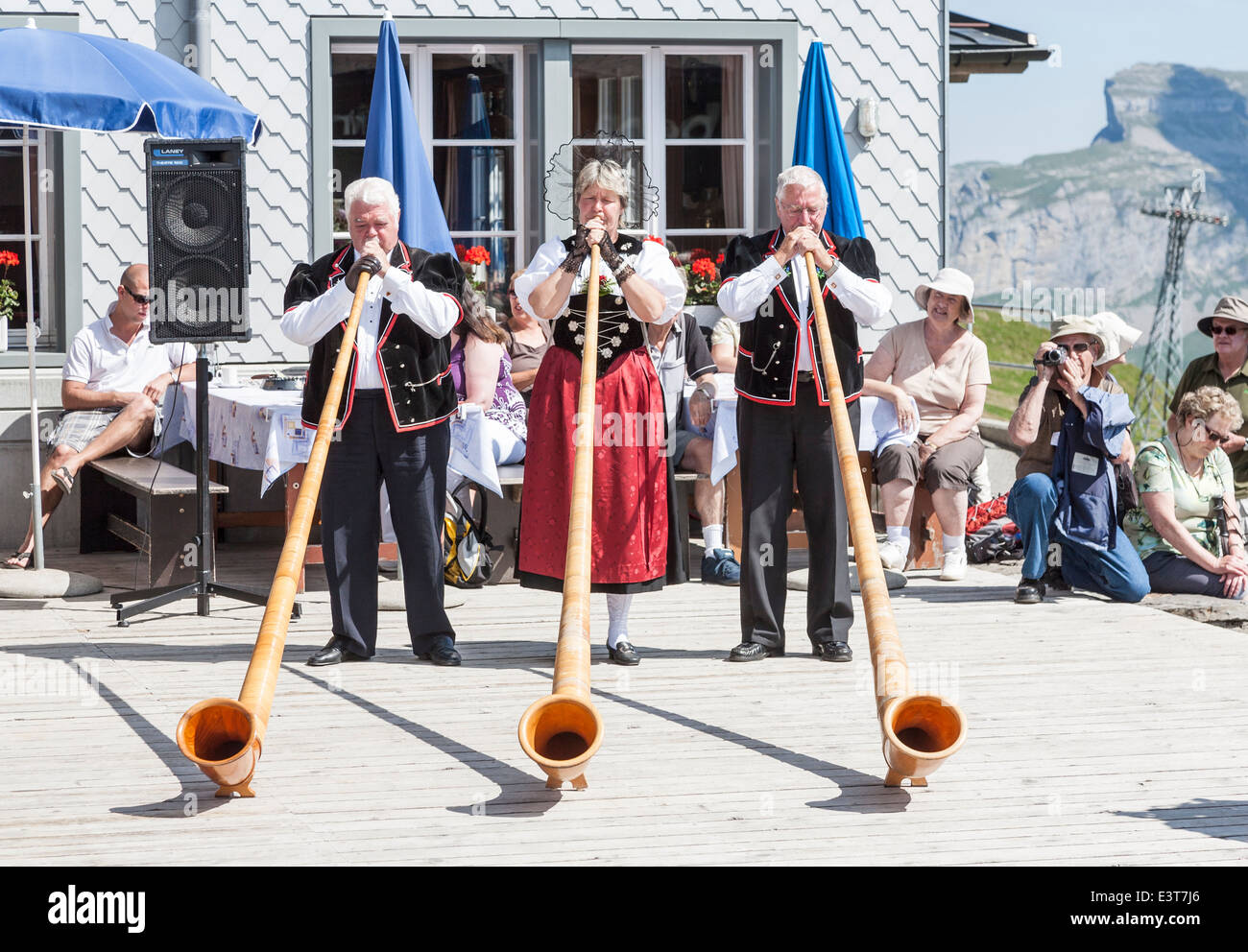 Swiss musicians in traditional national costume playing the alpenhorn in Mannlichen, Wengen, Bernese Oberland, Switzerland Stock Photo