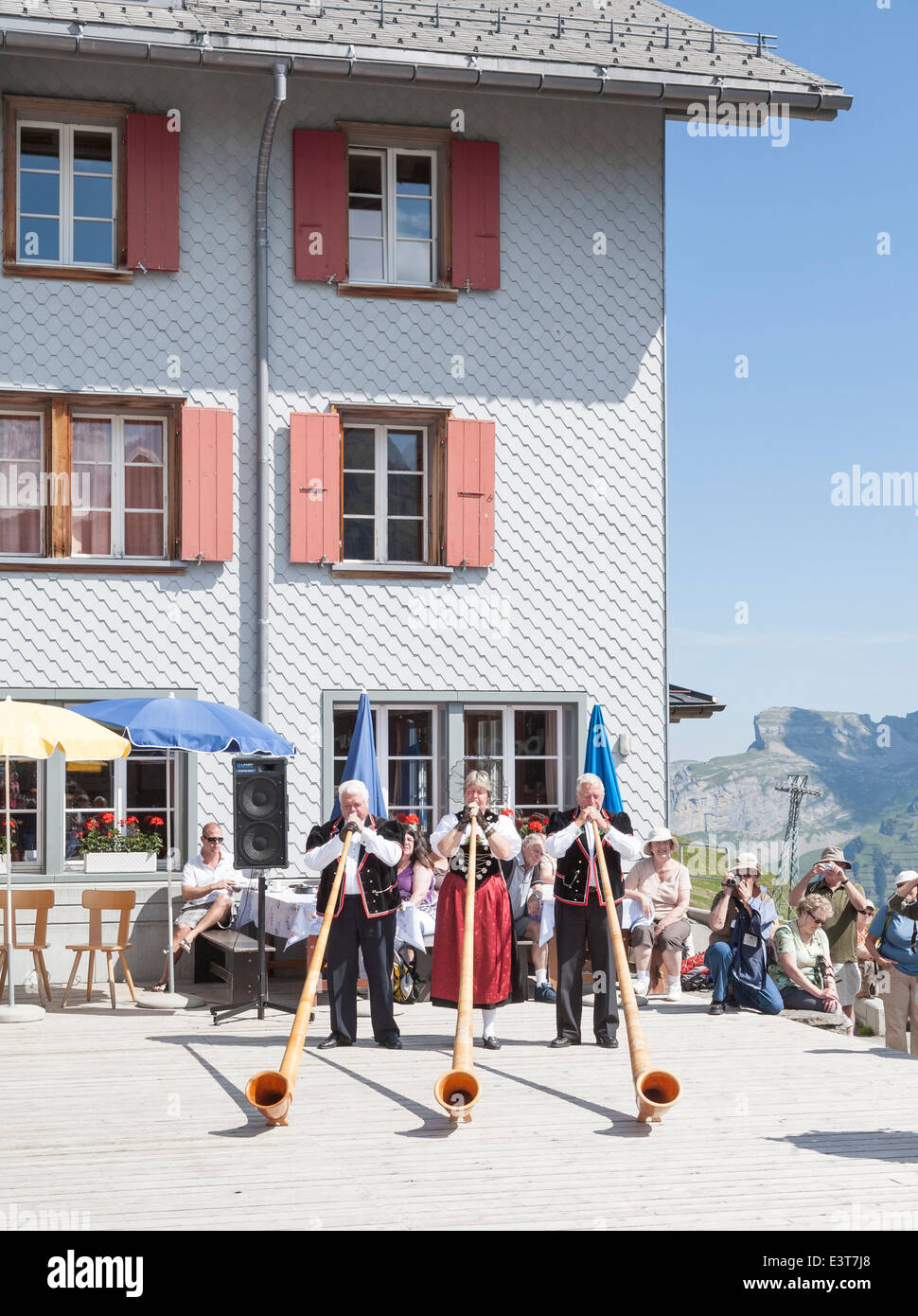 Swiss musicians in traditional national costume playing the alpenhorn in Mannlichen, Wengen, Bernese Oberland, Switzerland Stock Photo
