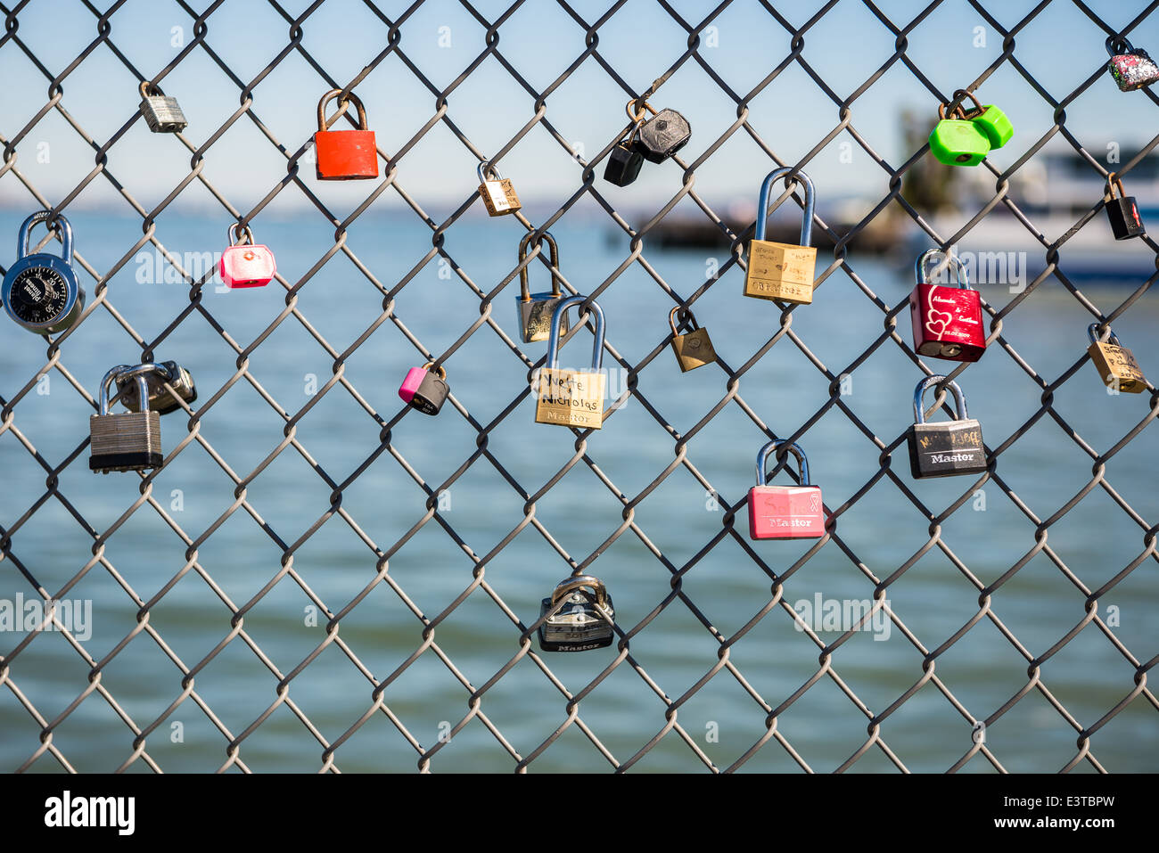 Padlocks tied to wire railing by couples on Embarcadero, San Francisco